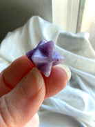 lepidolite merkaba star held between fingers, polished mini crystal for stress relief, intuition and inner peace