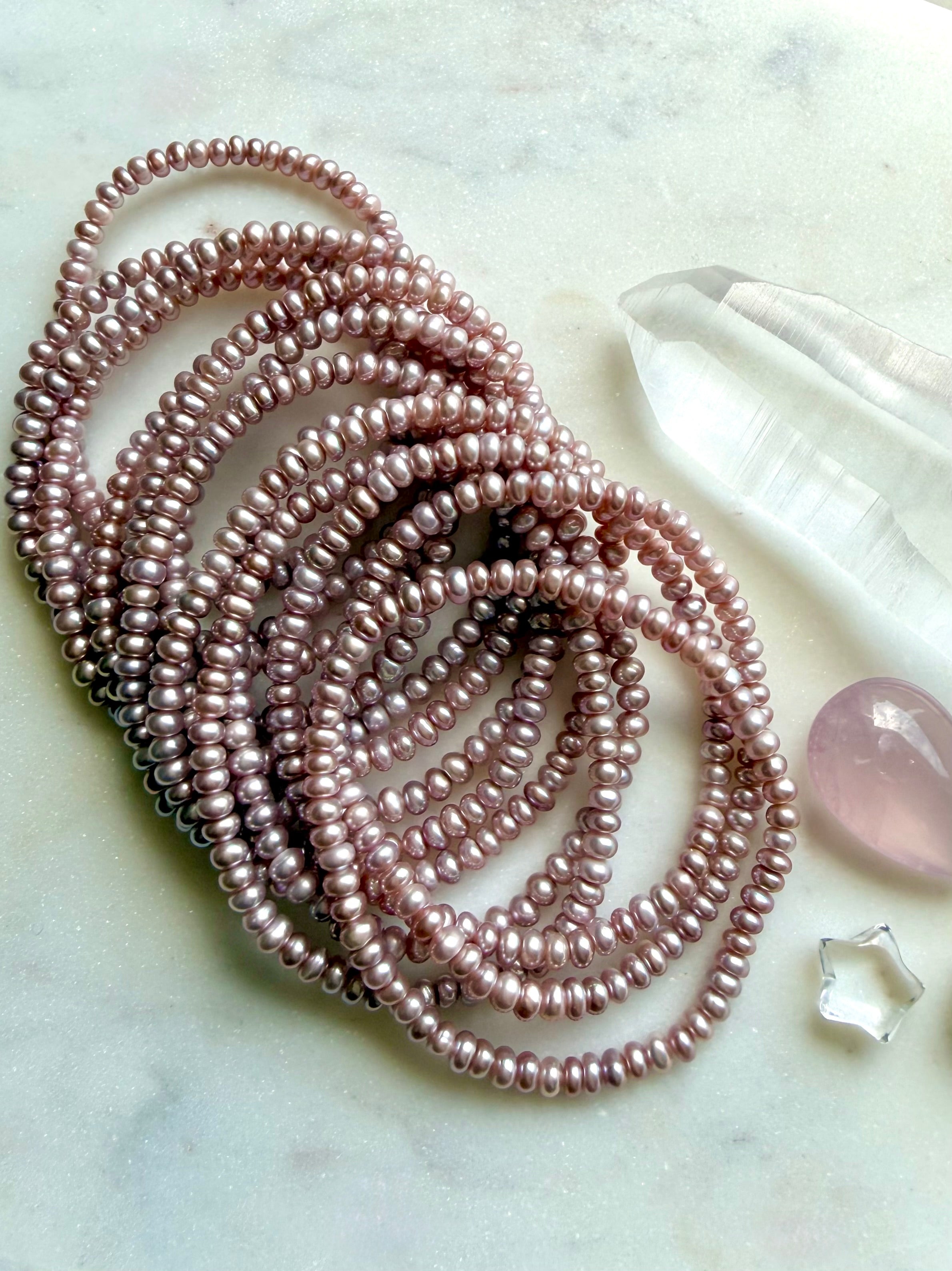 group of pink freshwater pearl bracelets arranged on surface, soft lilac pearl jewelry with natural luster and organic variation