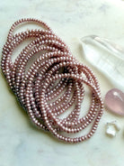 group of pink freshwater pearl bracelets arranged on surface, soft lilac pearl jewelry with natural luster and organic variation