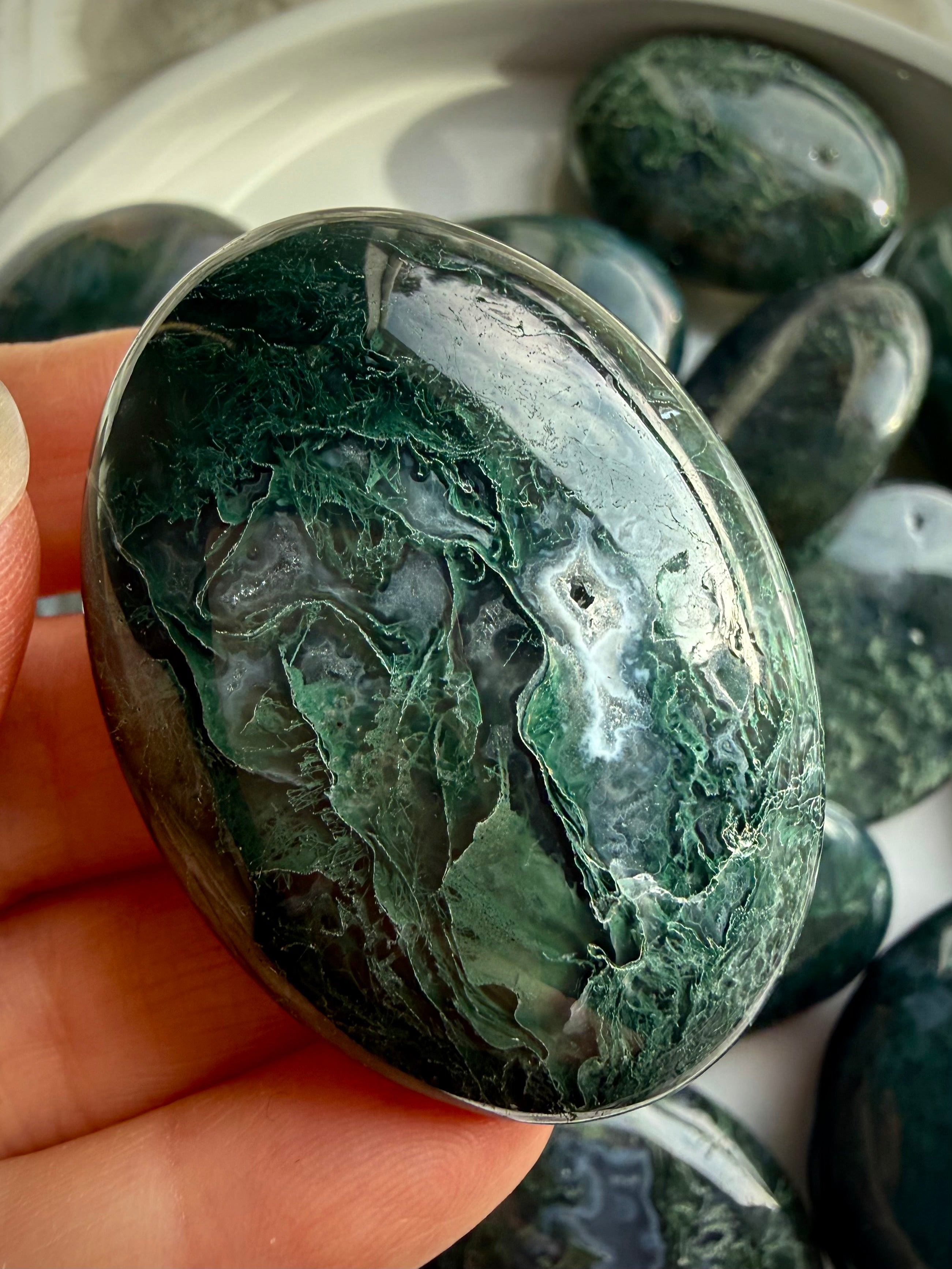 Moss agate palm stone held in hand, polished grounding crystal with green moss inclusions for calm and stability