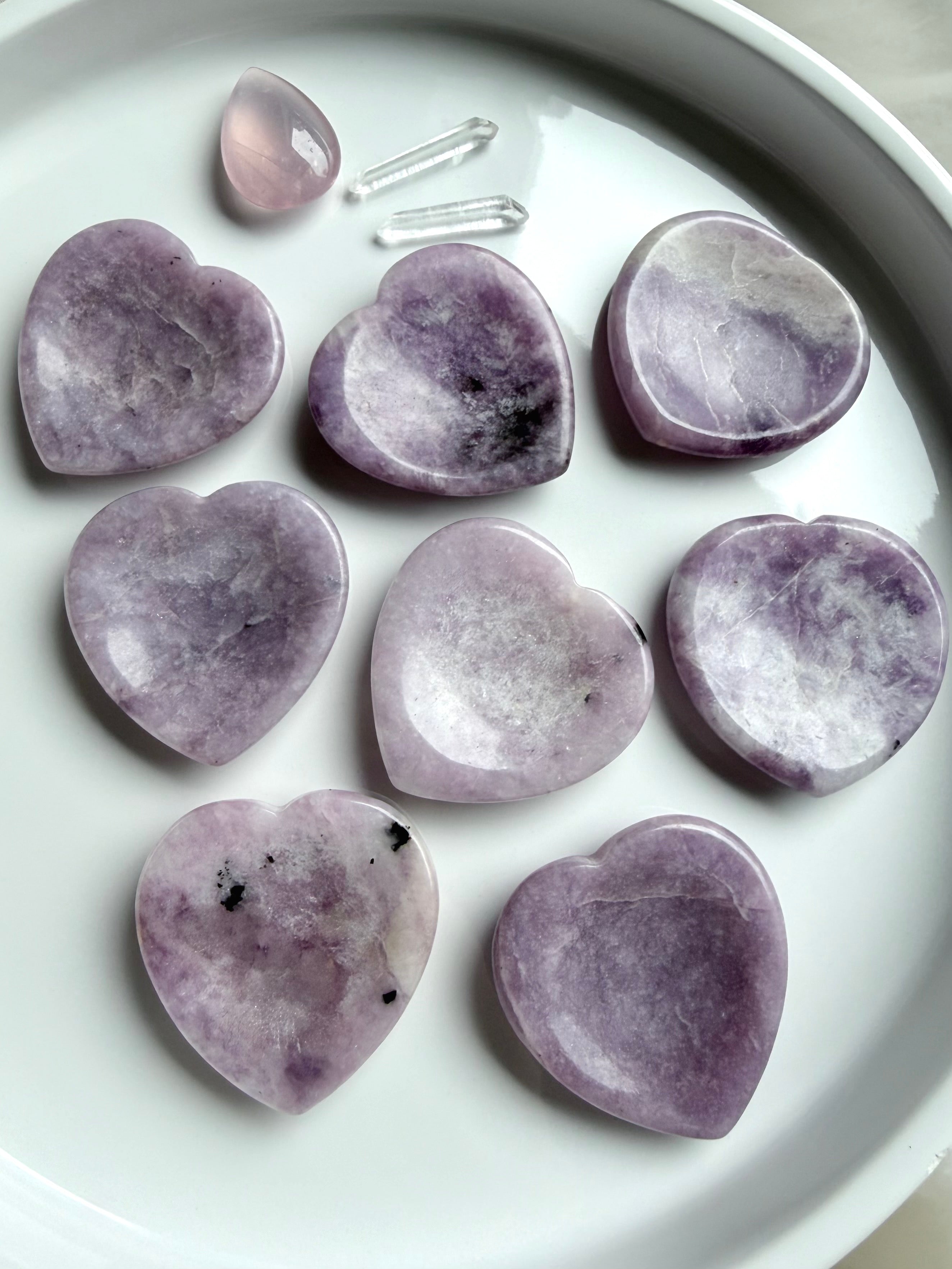 Lepidolite heart worry stones on white tray with mottled lilac purple and white crystal patterns