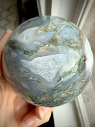 Moss Agate geode sphere showing large sparkling Quartz crystal cave framed by white Quartz and gray chalcedony