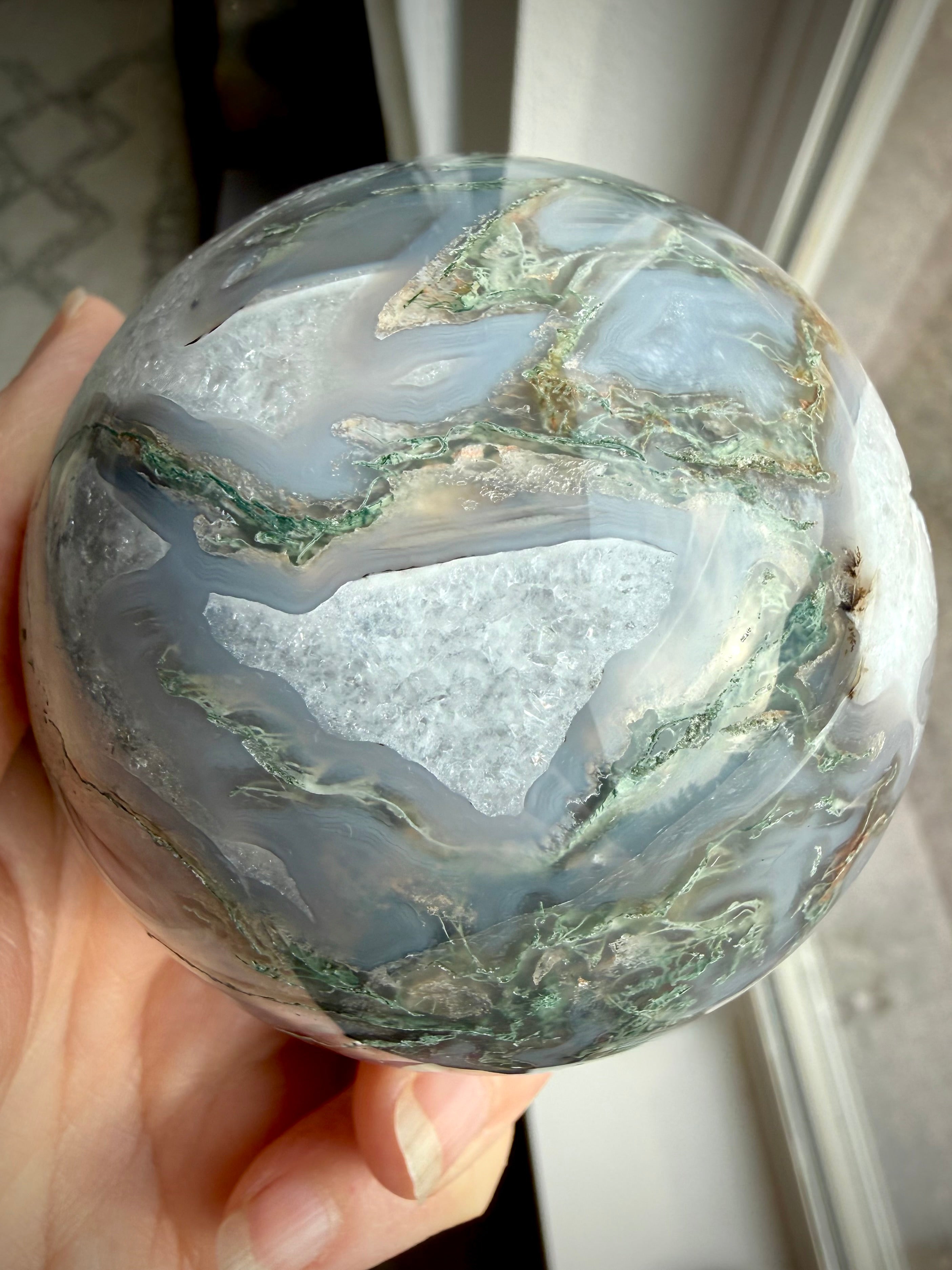 Moss Agate geode sphere showing large sparkling Quartz crystal cave framed by white Quartz and gray chalcedony