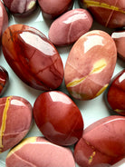 closeup of polished Mookaite Jasper palm stones with warm desert tones and organic banding for emotional stability