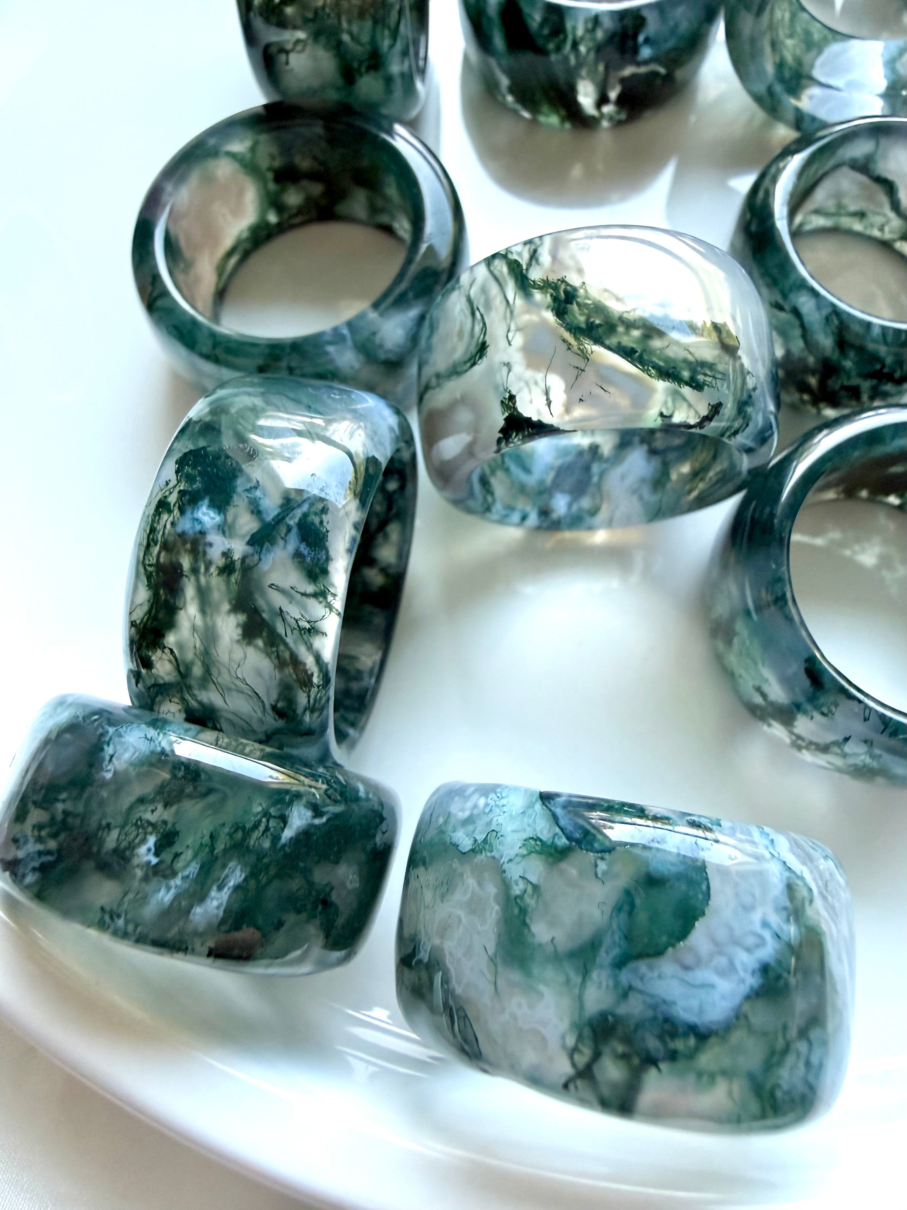 collection of translucent moss agate rings with forest green and gray inclusions, grounding crystal jewelry for heart chakra healing