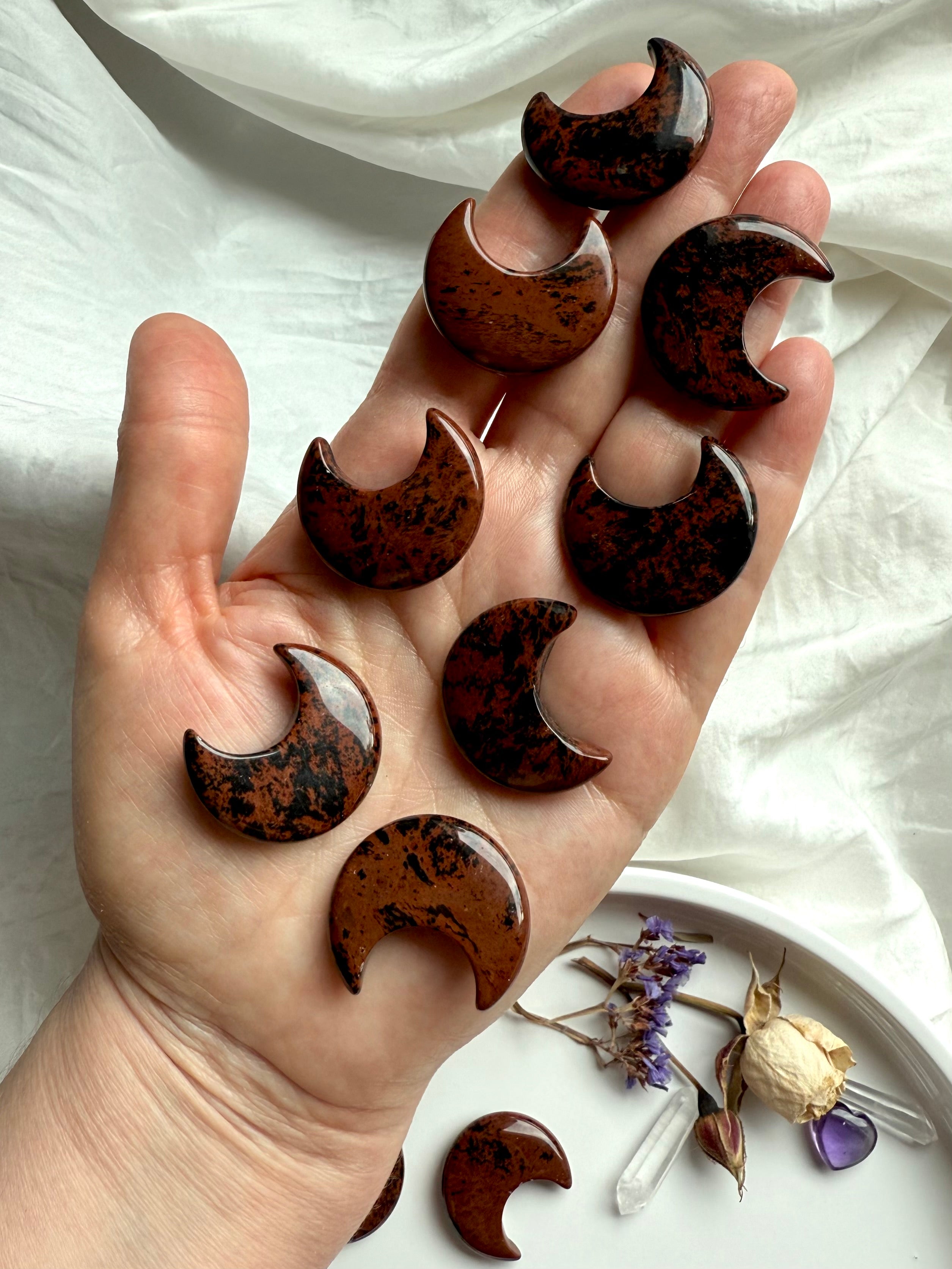Mahogany Obsidian crescent moon carvings on hand. Root + Sacral Chakra stone for resilience + protection.
