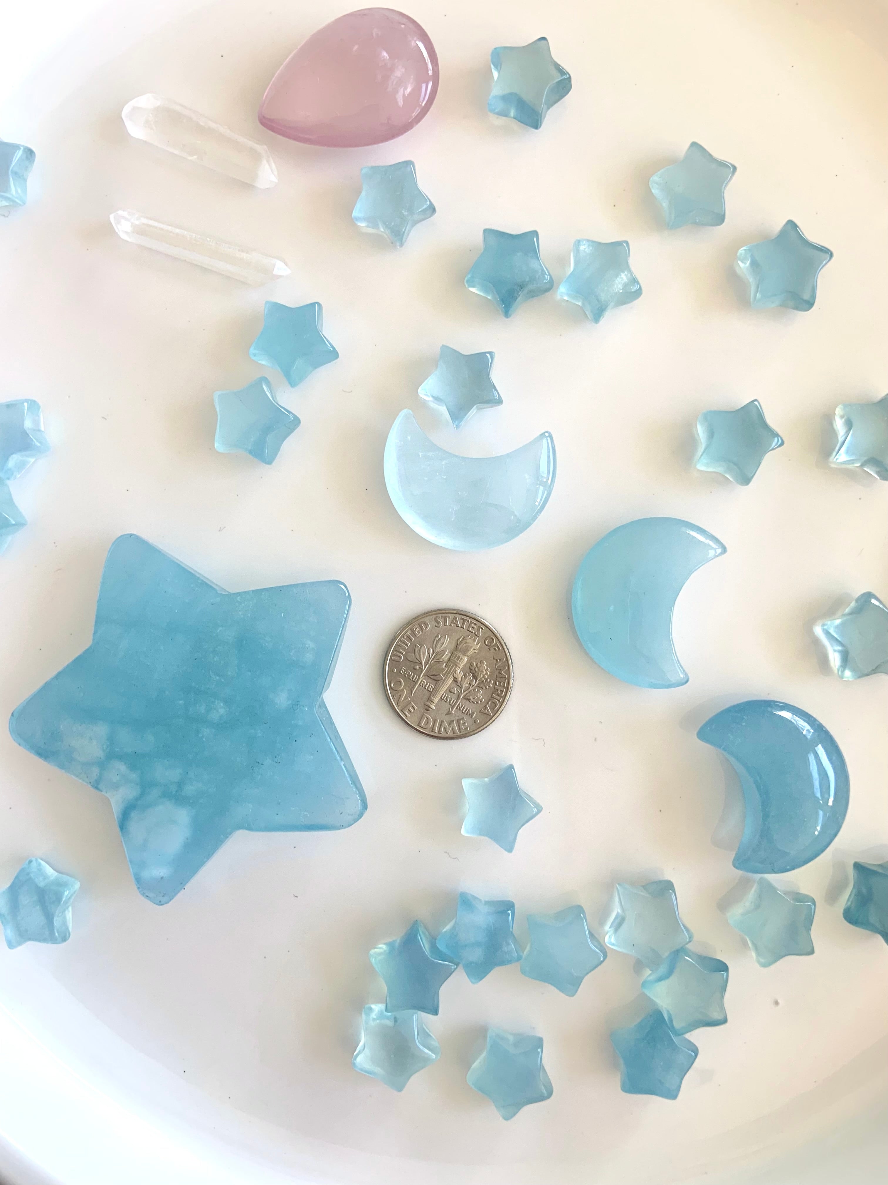 Mini Aquamarine moon and star carvings next to a dime for scale