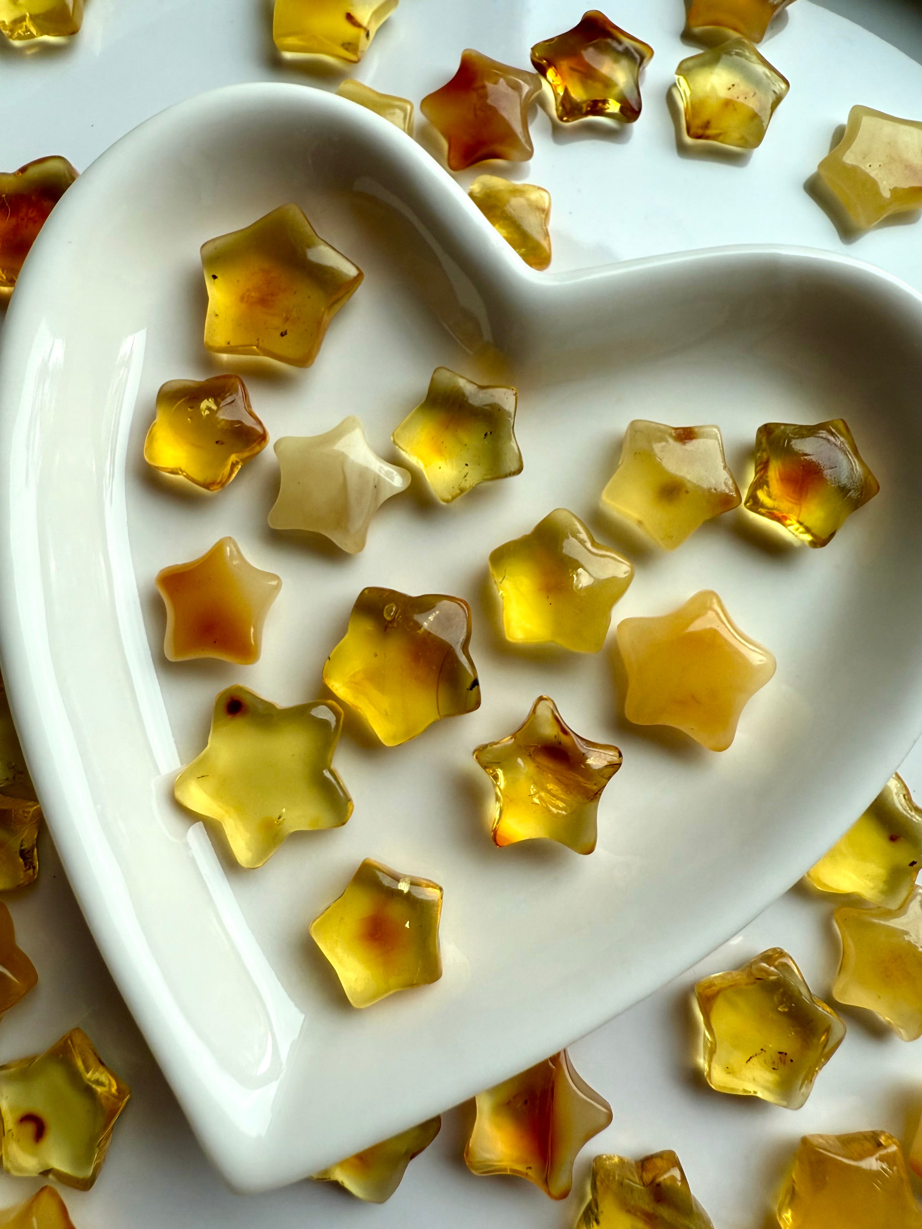 Golden Amber Star carvings in a heart-shaped dish – crystals for light, joy, and Solar Plexus healing