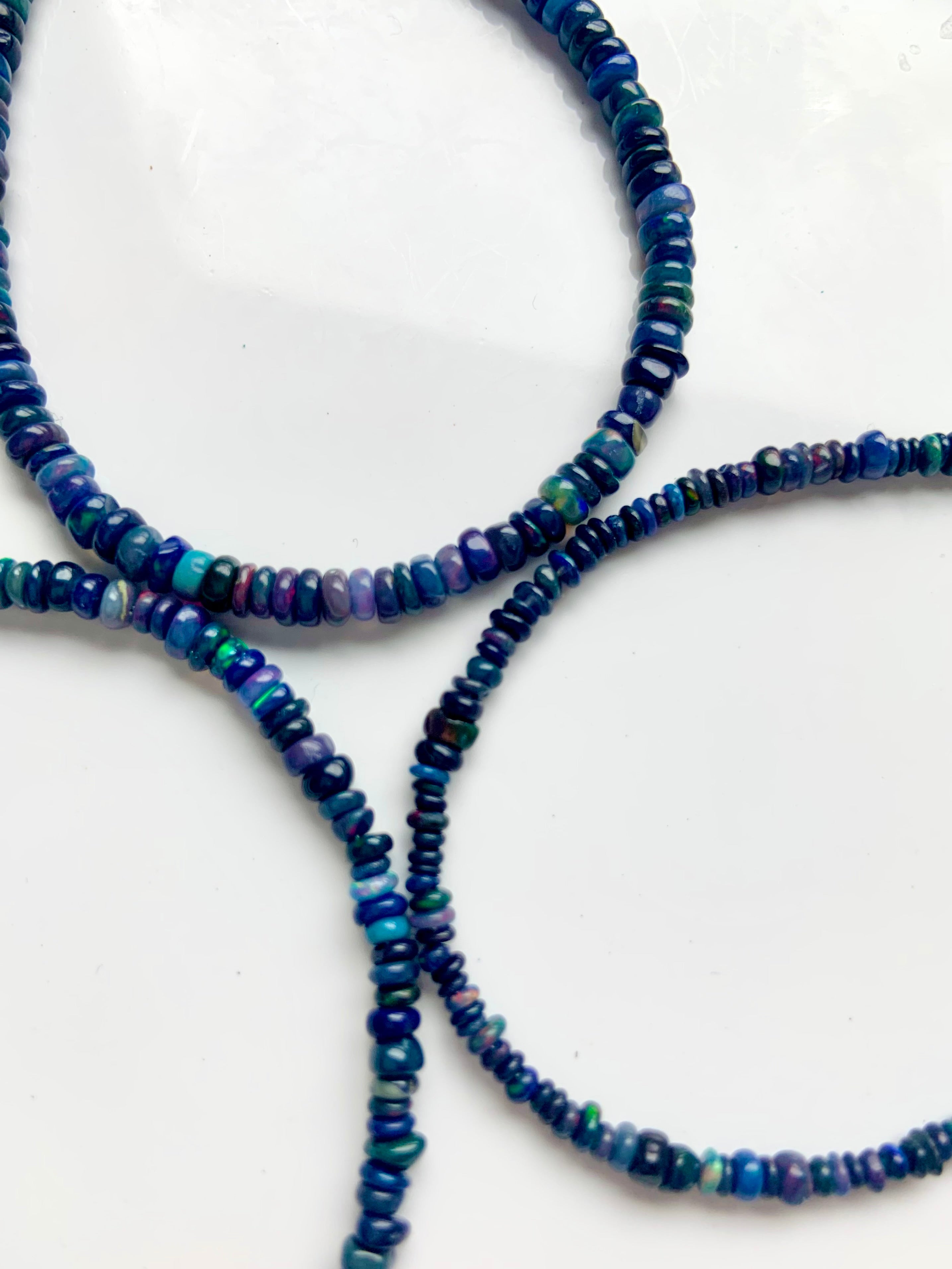 Close-up of three Black Fire Opal bracelets, one in each bead size — 2.9mm, 3.4mm, and 3.8mm — genuine Ethiopian opal jewelry.