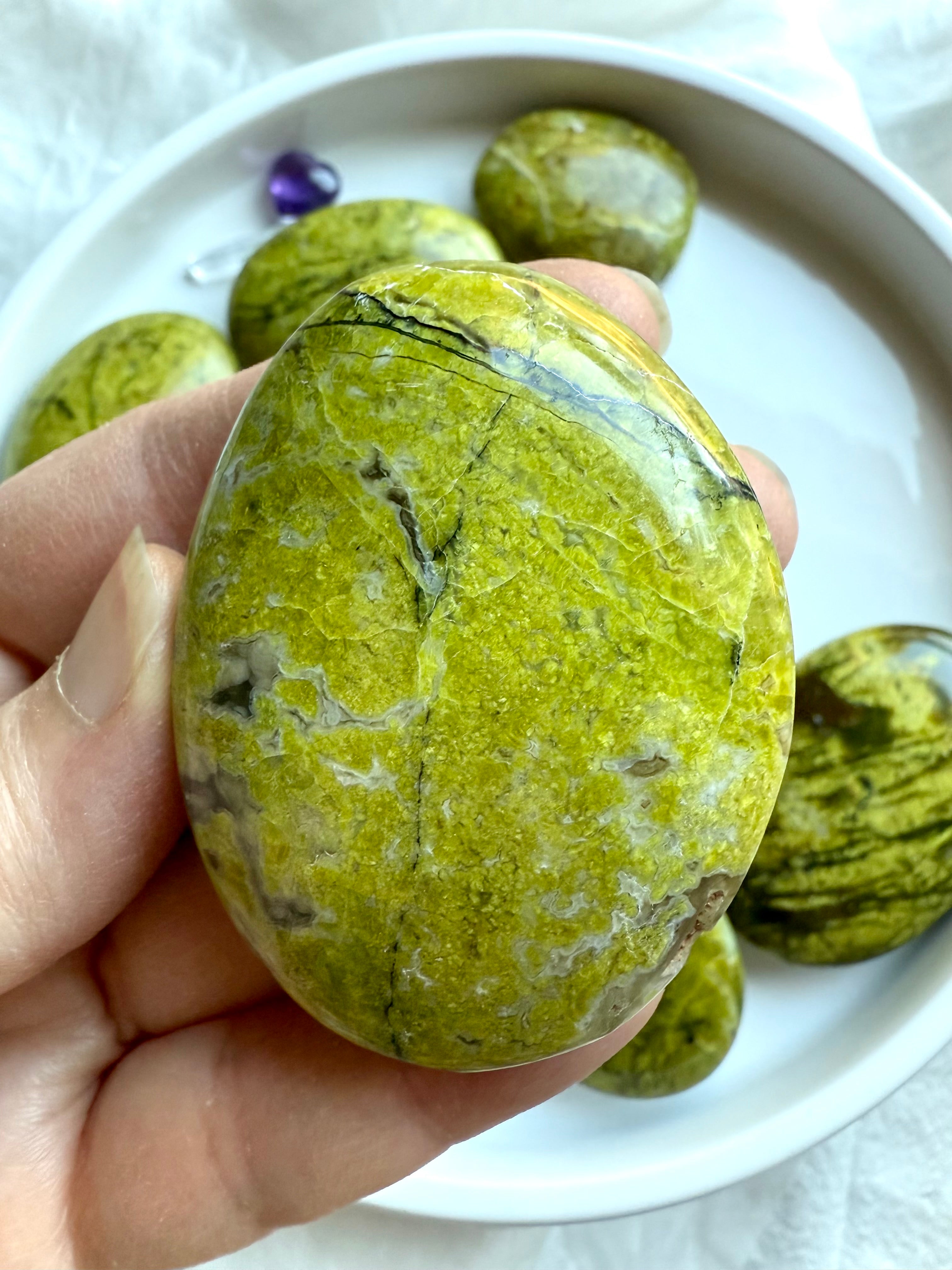 Close-up of a Green Opal palm stone with golden veins and earthy inclusions — Pistachio Opal healing crystal for joy and inner growth.