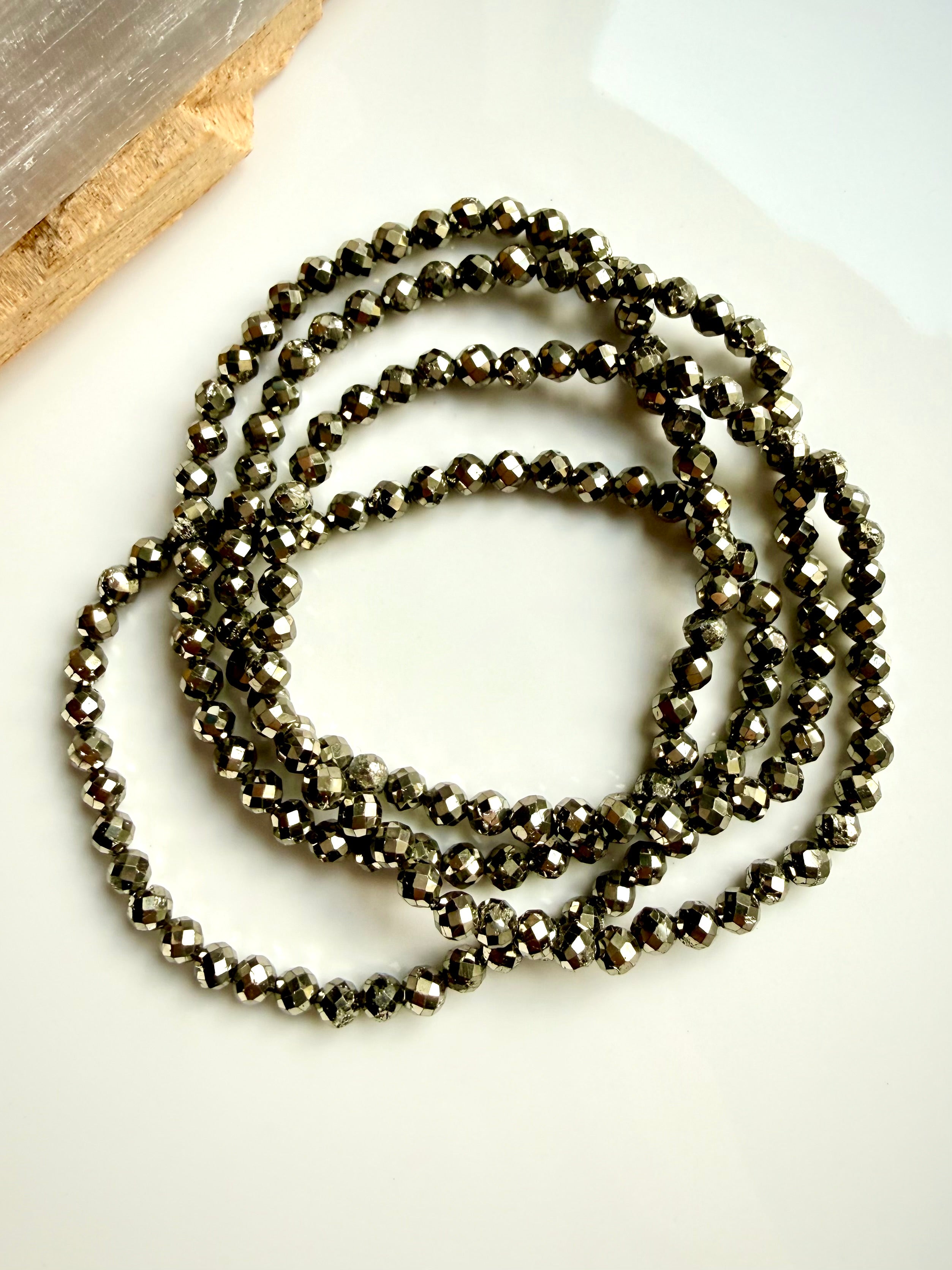 coiled pyrite bracelet set on neutral surface showing flexible stretch design and polished beads