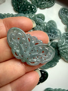 Closeup of Blue Water Jade butterfly carving held in hand showing glossy translucent jadeite