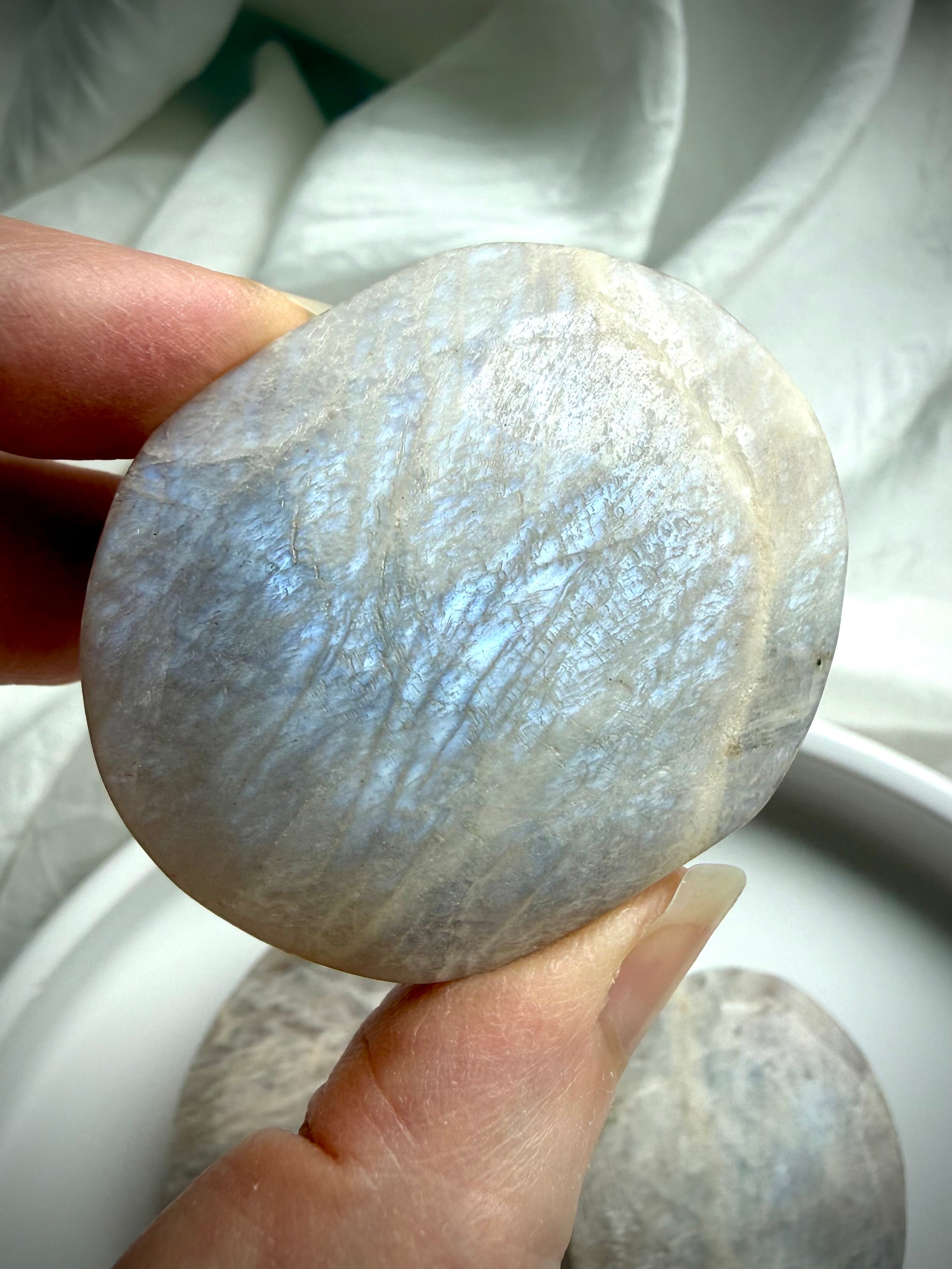 belomorite moonstone palm stone with electric blue flash and natural feldspar shimmer in hand