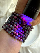 Ruby Sapphire bracelets under UV light revealing fluorescent ruby gemstones and natural sapphire beads