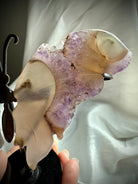 Close-up of amethyst druzy geode along the carved agate butterfly wing, highlighting lavender crystals and natural banding.