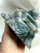 Back view of a Large Moss Agate Laughing Buddha statue showing scenic inclusions and carving detail