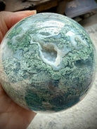 Druzy Moss Agate crystal ball close up with sparkling cave, Quartz pocket, and intricate moss-like inclusions