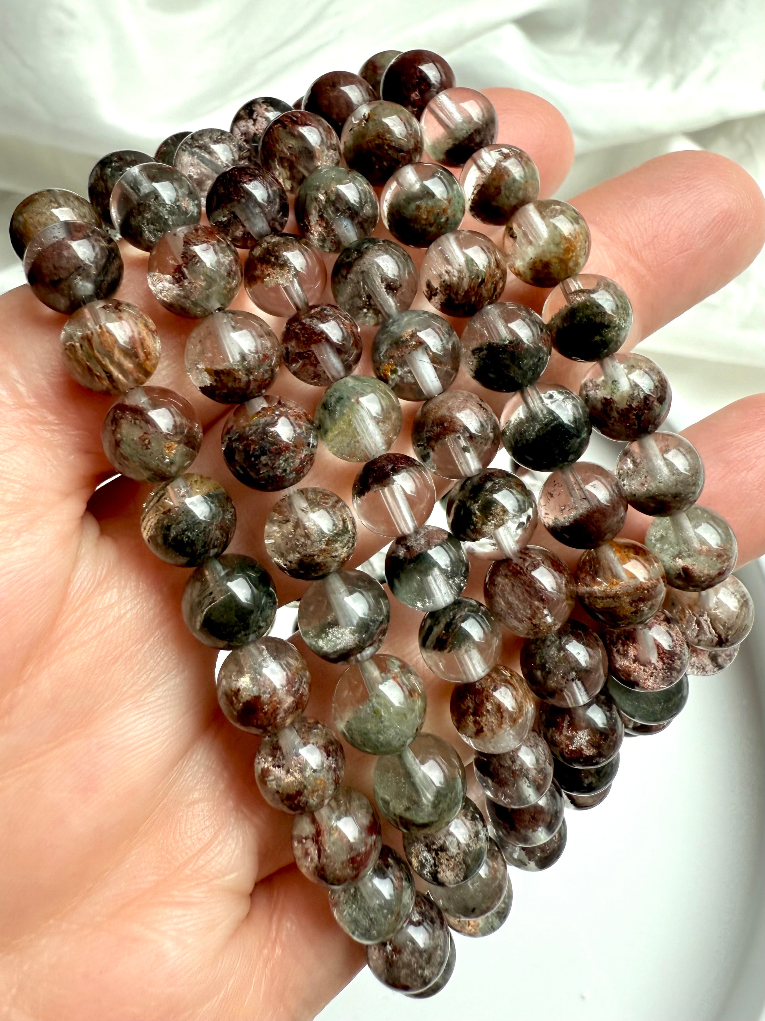 Hand holding Garden Quartz bracelets with scenic mineral formations inside transparent quartz spheres