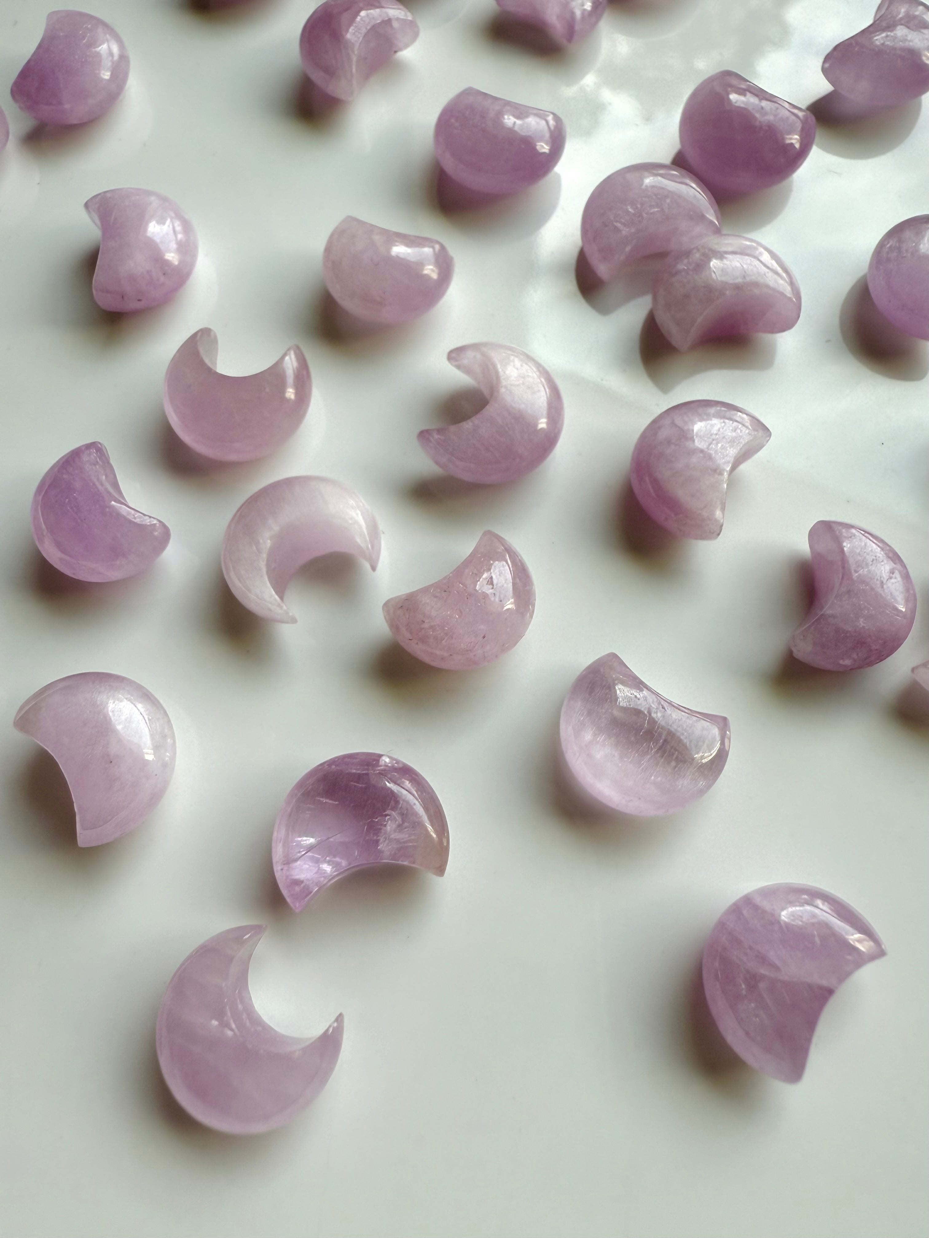 Mini Pink Kunzite crescent moons on a white plate — gentle pink crystal carvings for emotional healing & heart-centered energy work.