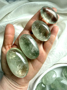 Hand holding Prasiolite palm stones showing size variation and green amethyst clarity