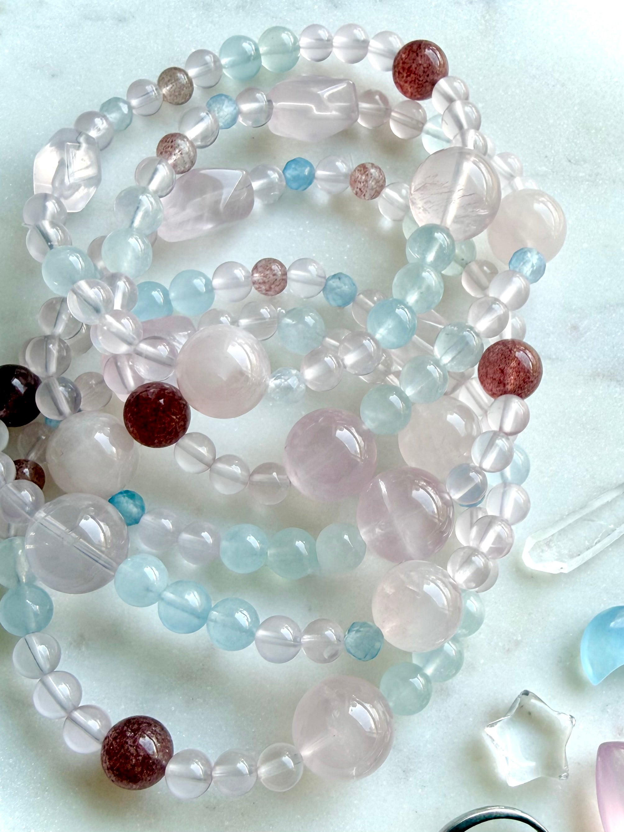 mixed gemstone bracelet worn on wrist with layered styling, pastel crystal jewelry featuring rose quartz aquamarine and blue topaz accents