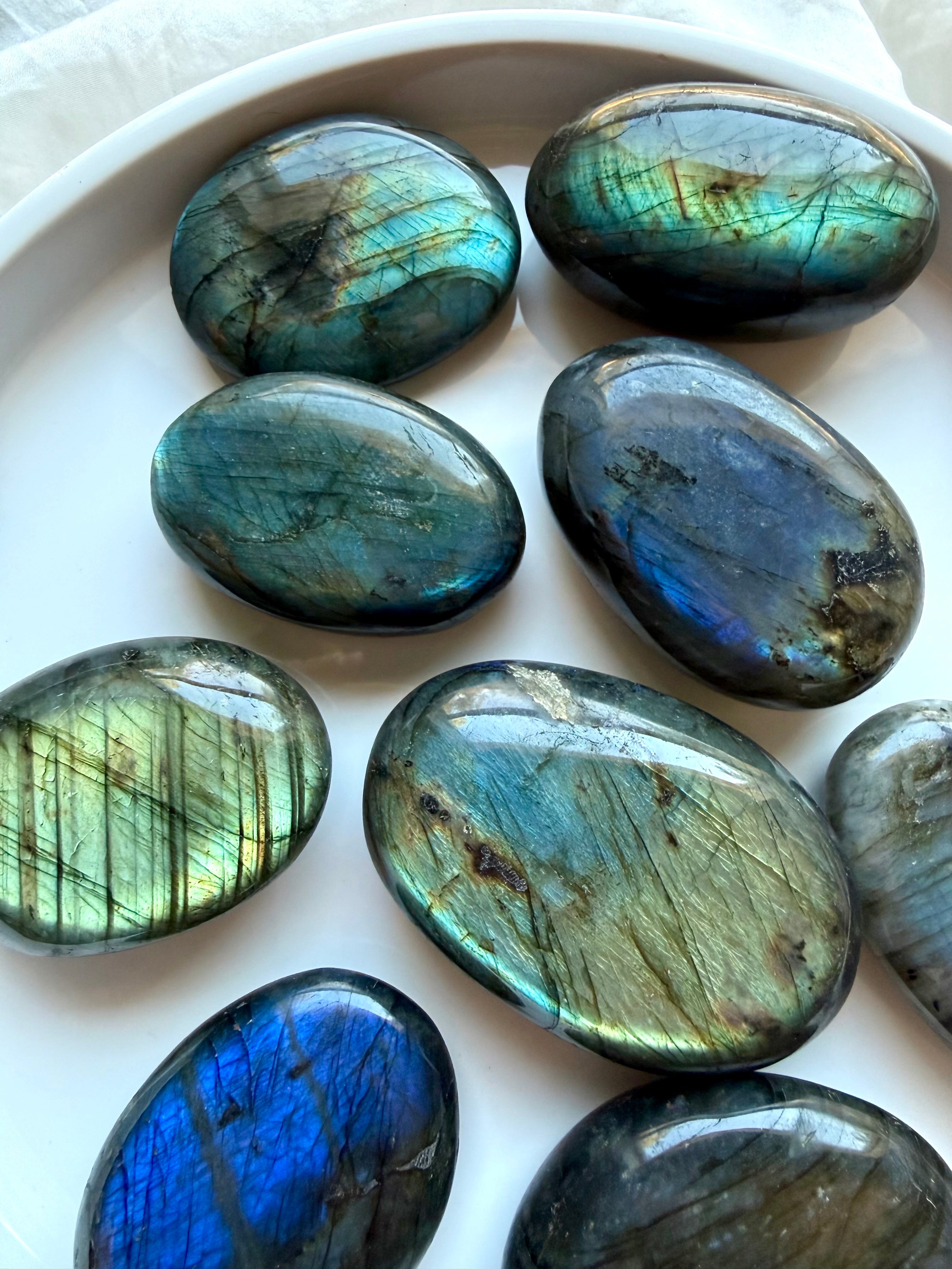 Labradorite palm stones displaying a range of blue, teal and green flash in assorted polished sizes