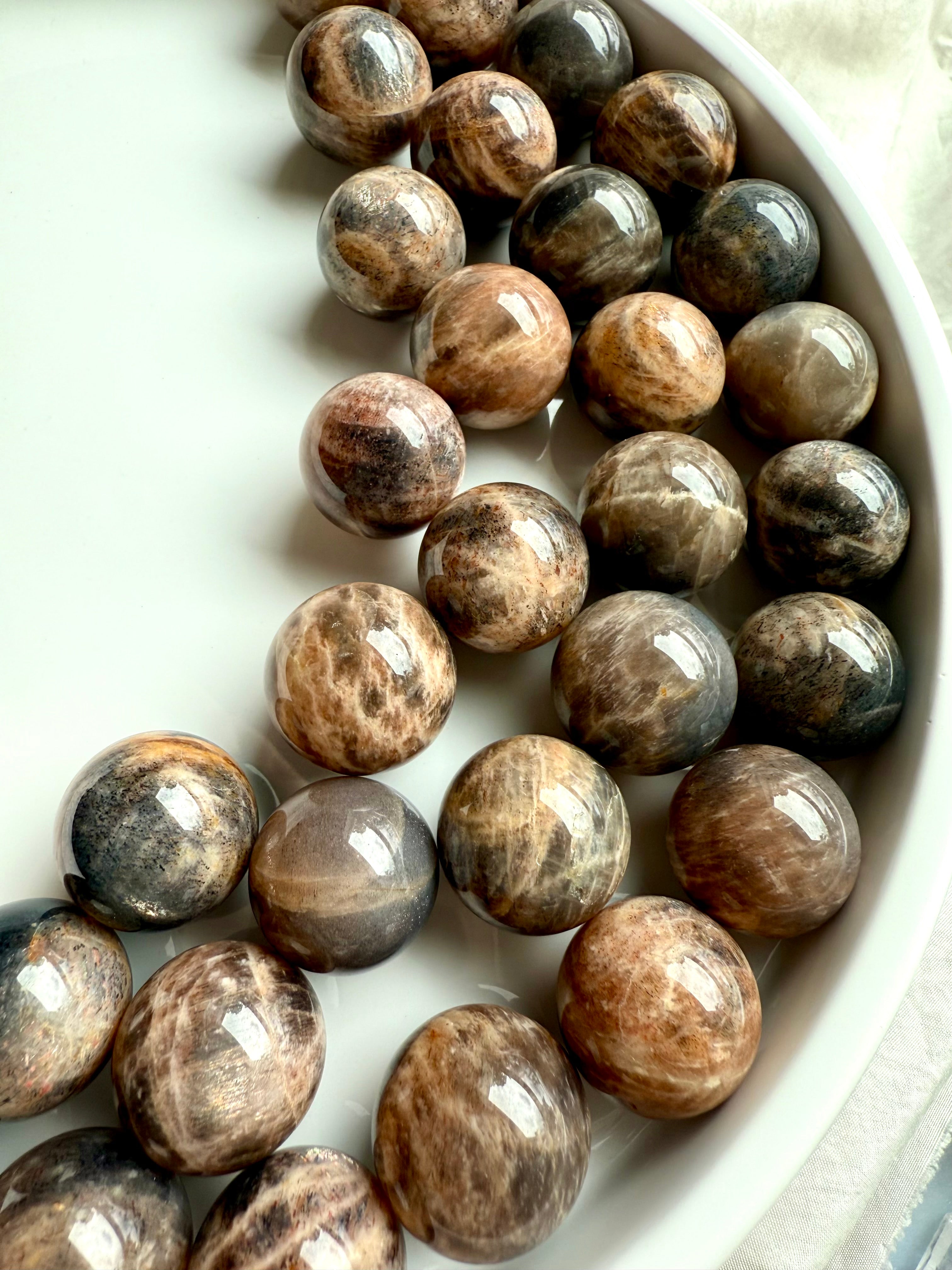 An array of Mini Black Moonstone spheres with golden chatoyant Sunstone flash and peachy tones