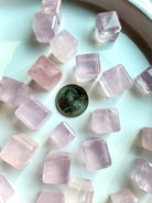 Mini rose quartz cube crystal shown next to a quarter for size reference, polished sacred geometry heart chakra stone