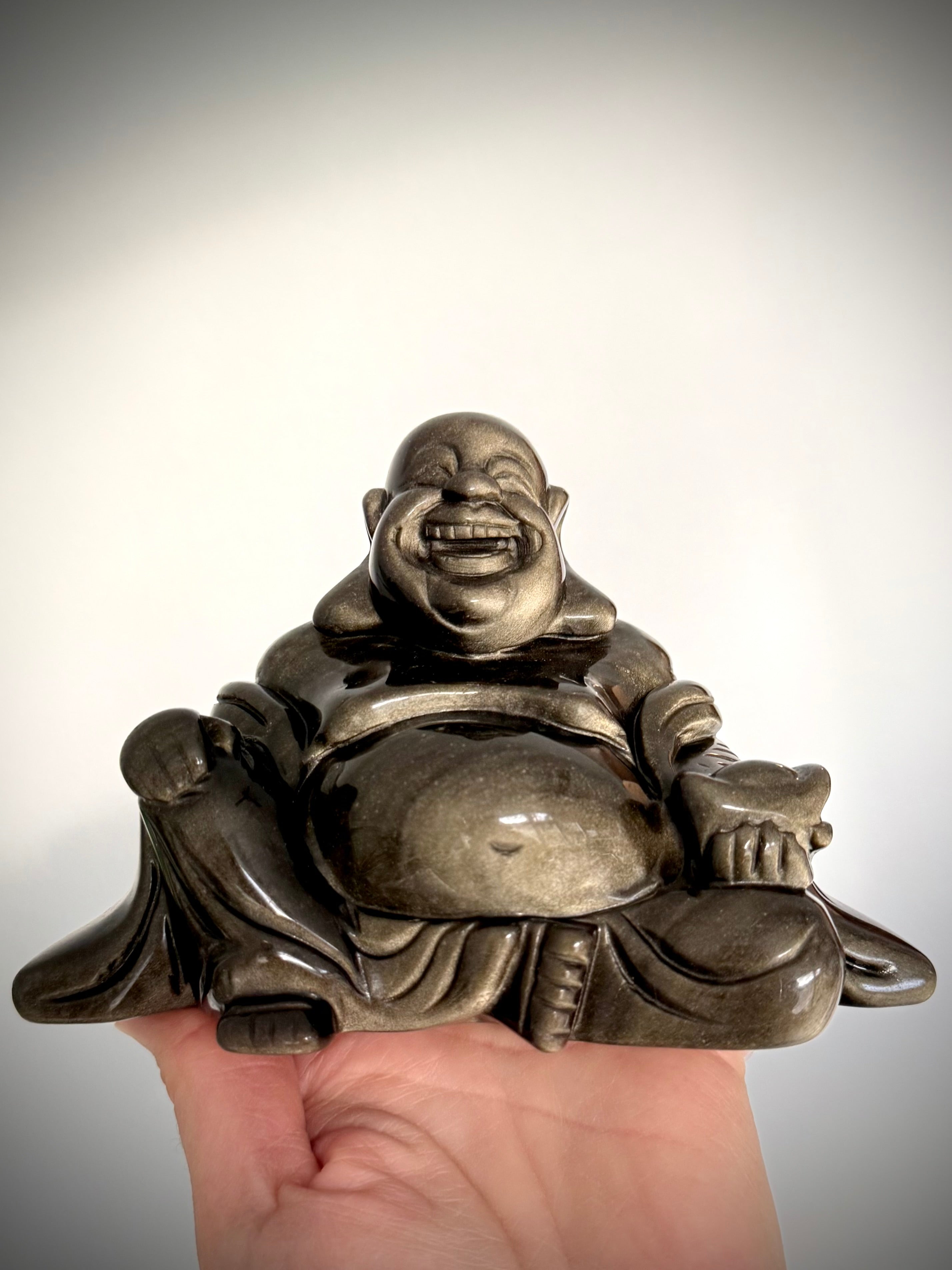 Close-up of laughing Buddha statue carved in Golden Sheen Obsidian, high-vibe crystal for manifestation and protection