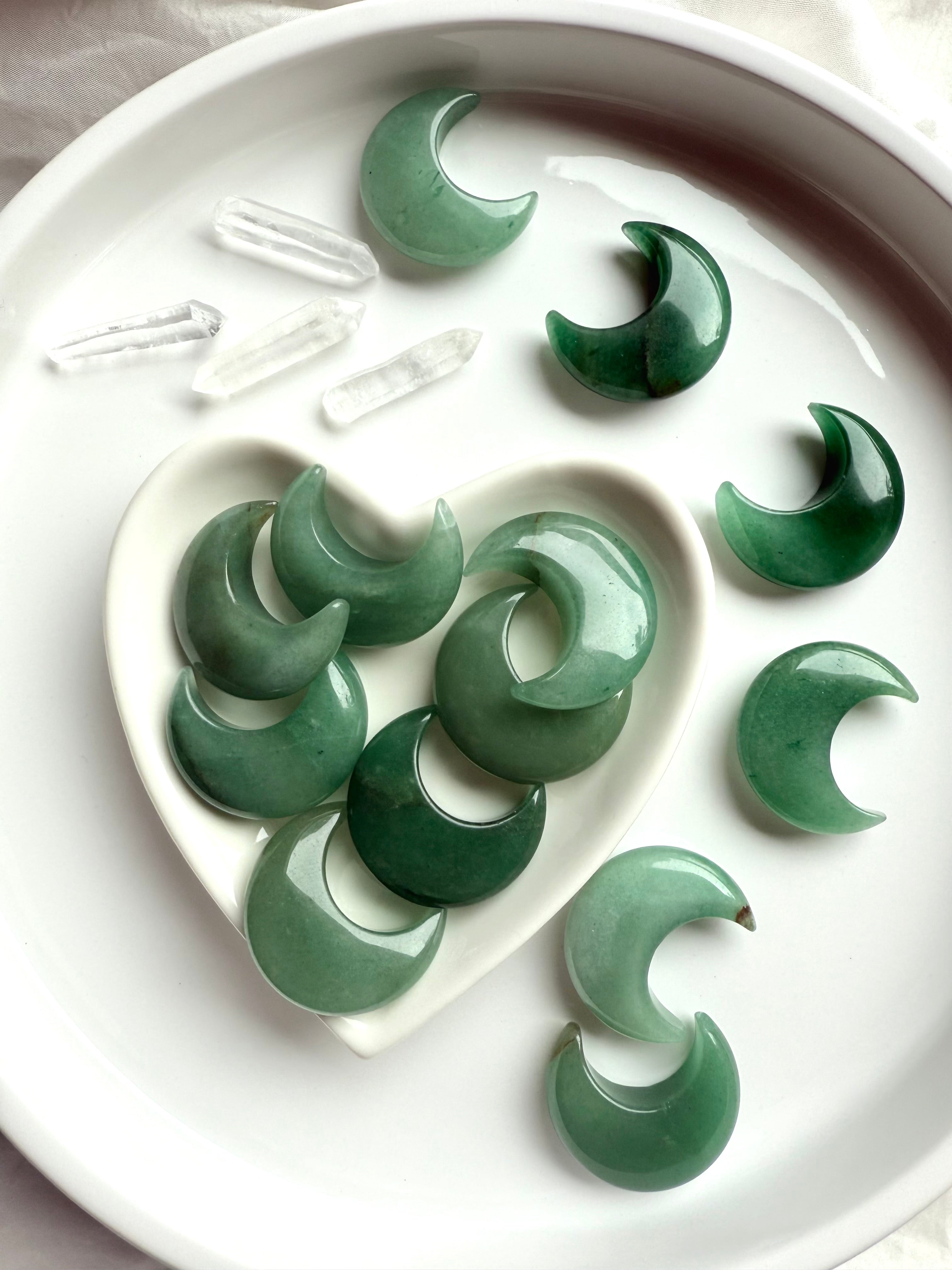 Green Aventurine moons in heart bowl surrounded by more moons and clear quartz points, grounding and healing crystal carvings
