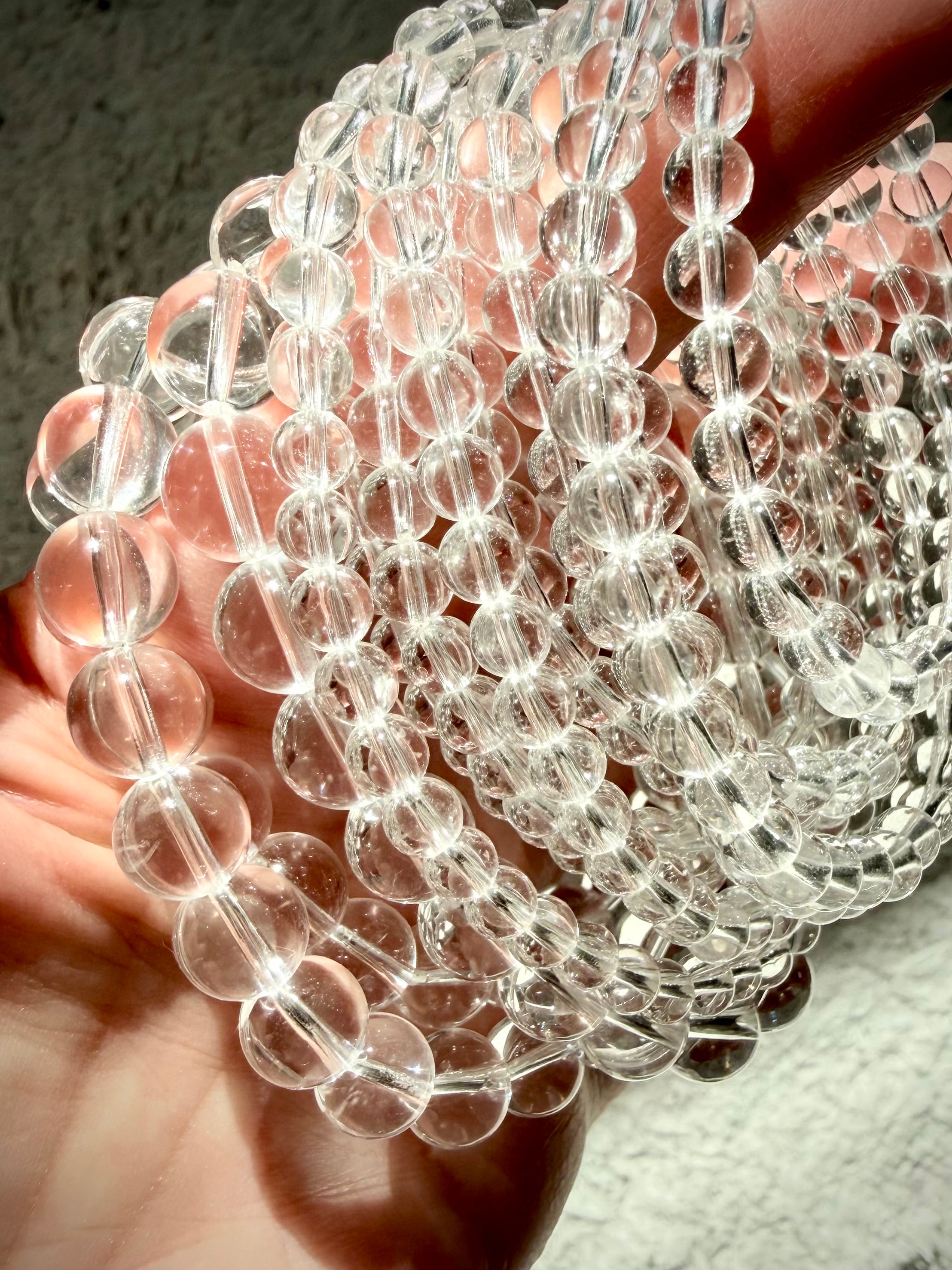 Clear Quartz bracelets arranged in a spiral showing multiple bead sizes and polished transparent crystal beads