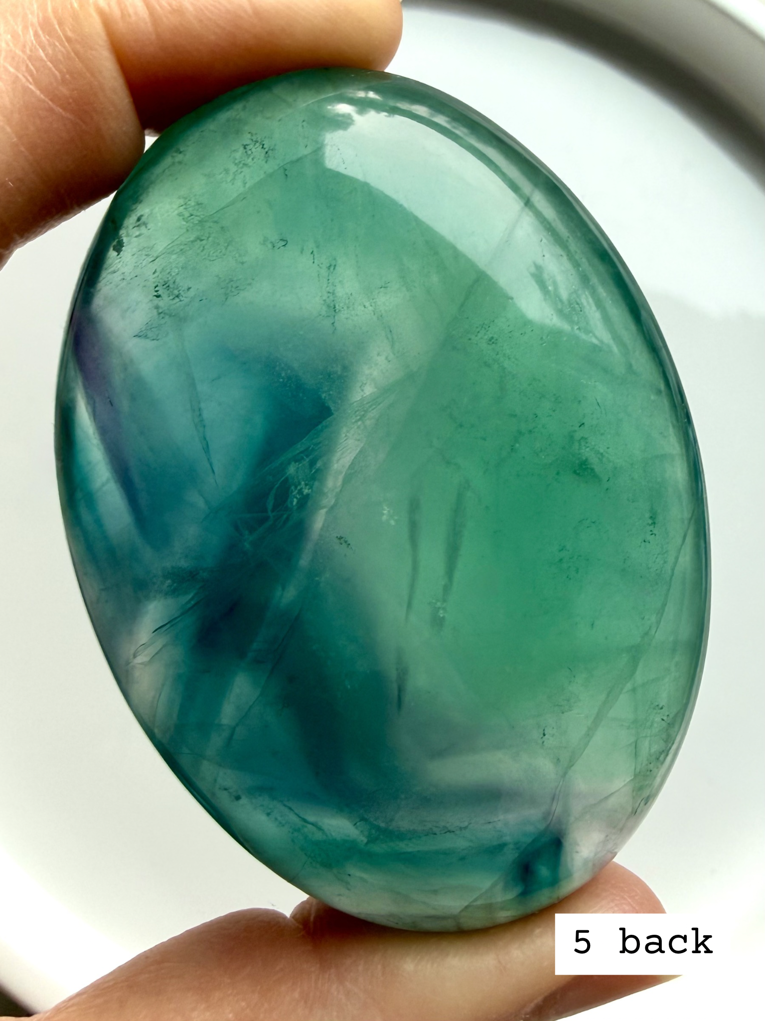 Teal fluorite palm stone #5 back view with rich blue green layers and glowing translucency