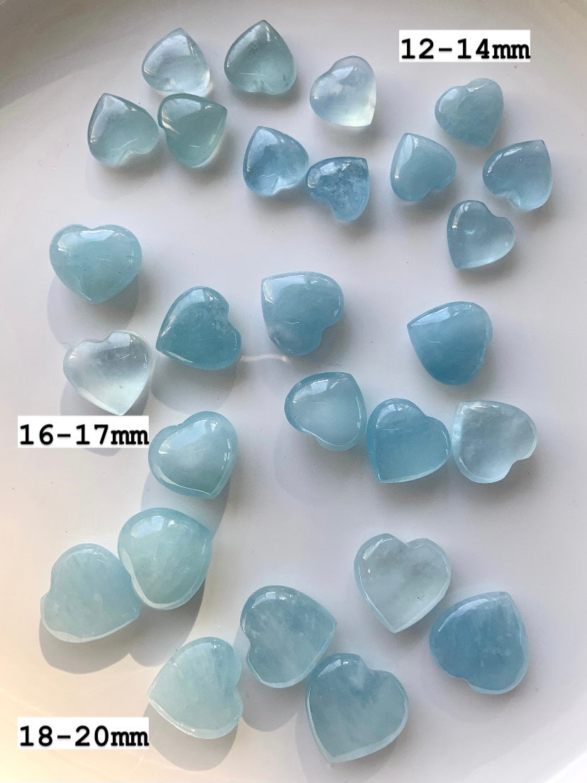 Aquamarine crystal hearts labeled with sizes 12–14mm, 16–17mm, 18–20mm — small gemstone hearts for throat chakra healing + peaceful communication.