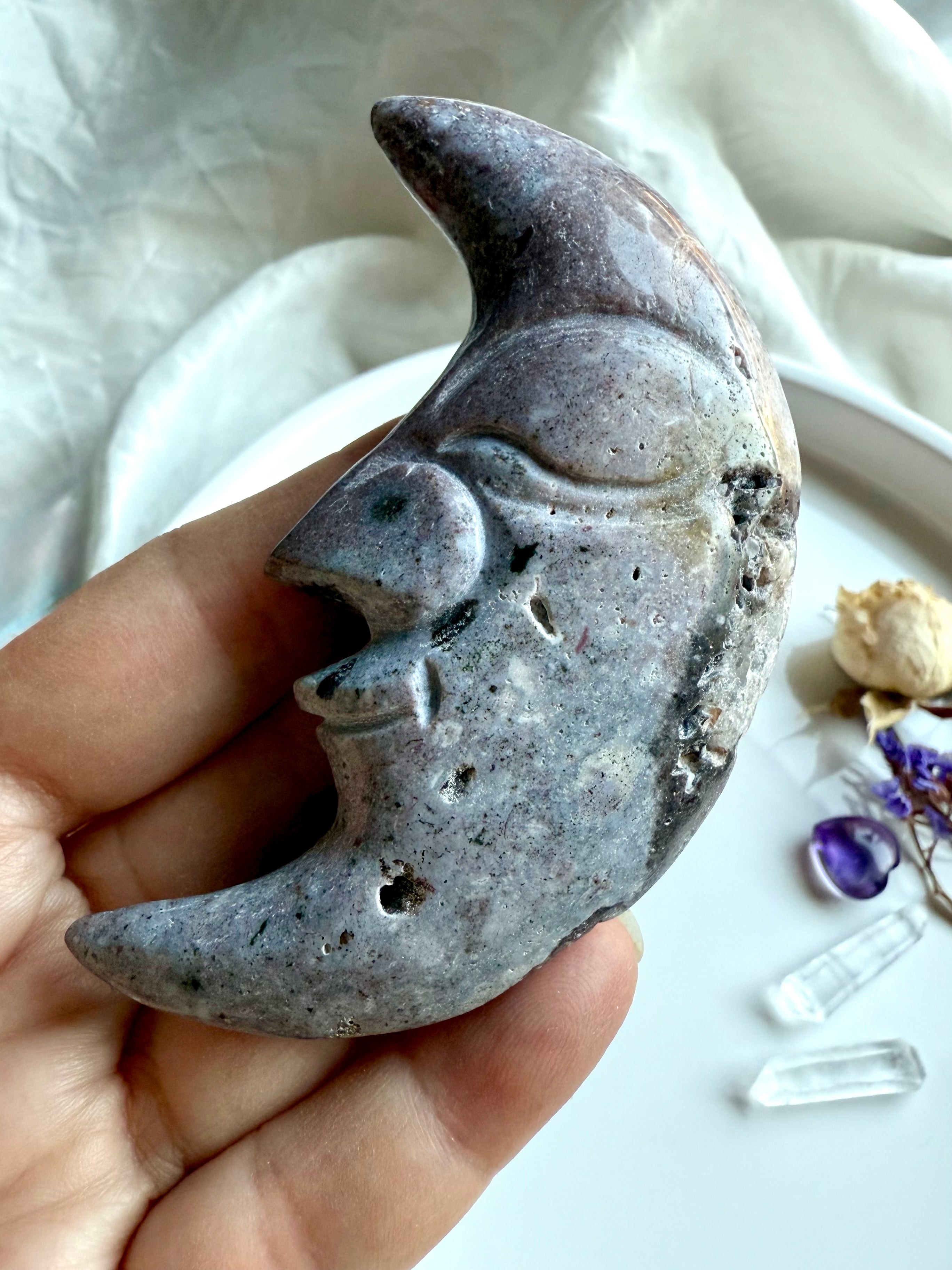 Purple Ocean Jasper moon face carving held in hand – crystal carving with unique banding and natural druzy details.