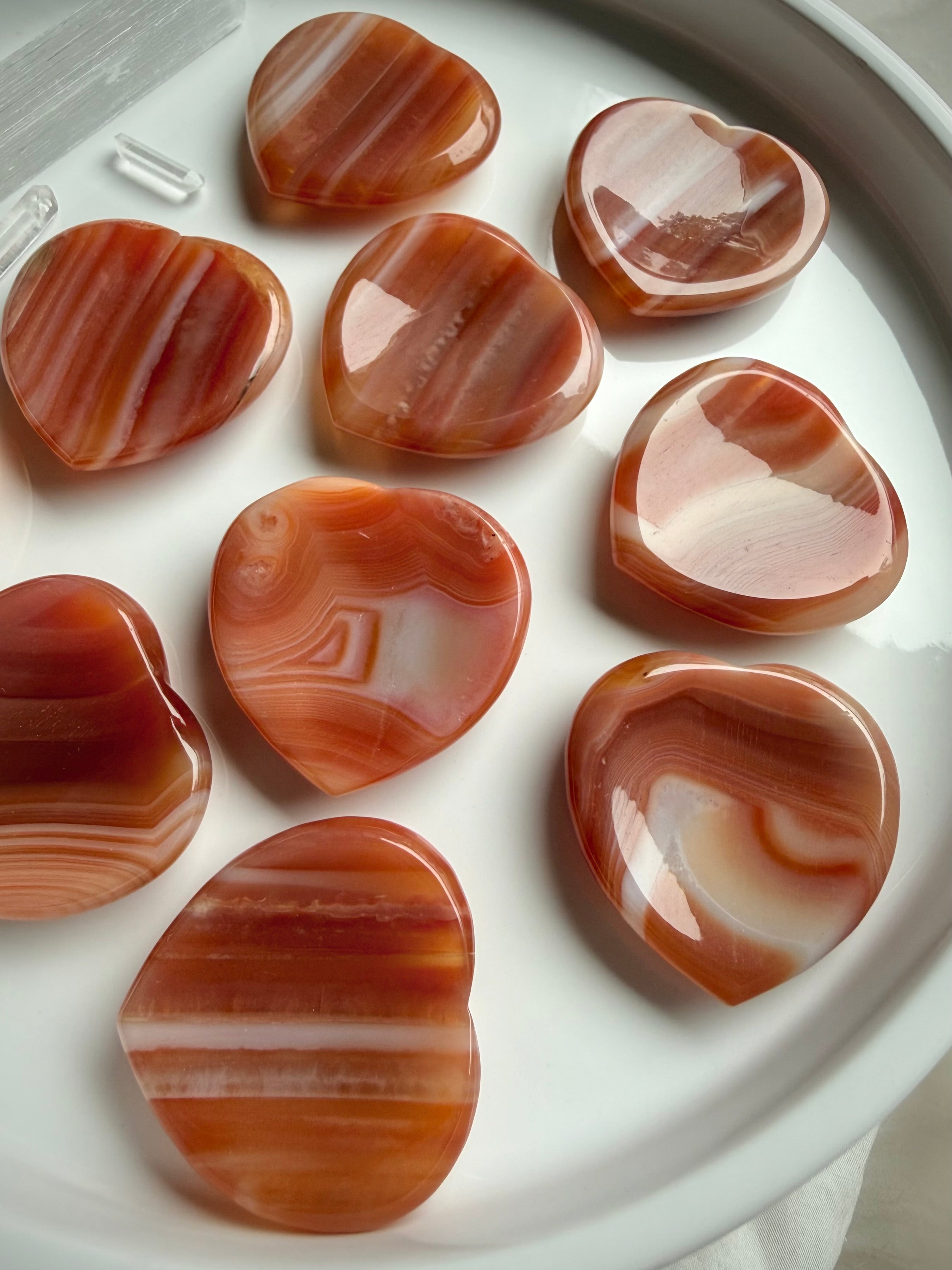 Polished carnelian crystal heart worry stones with natural banding and warm orange tones
