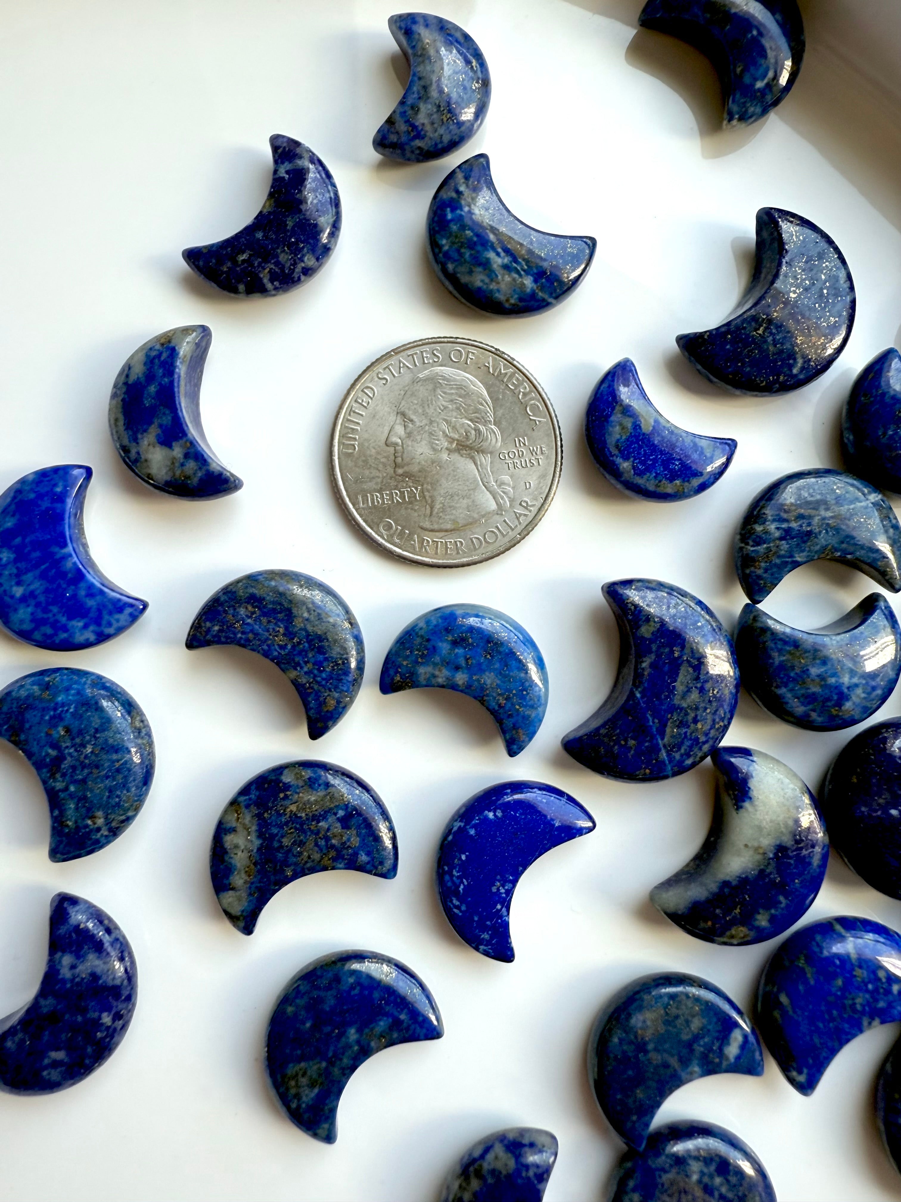 Mini Lapis Lazuli moon carvings next to a US quarter for size comparison
