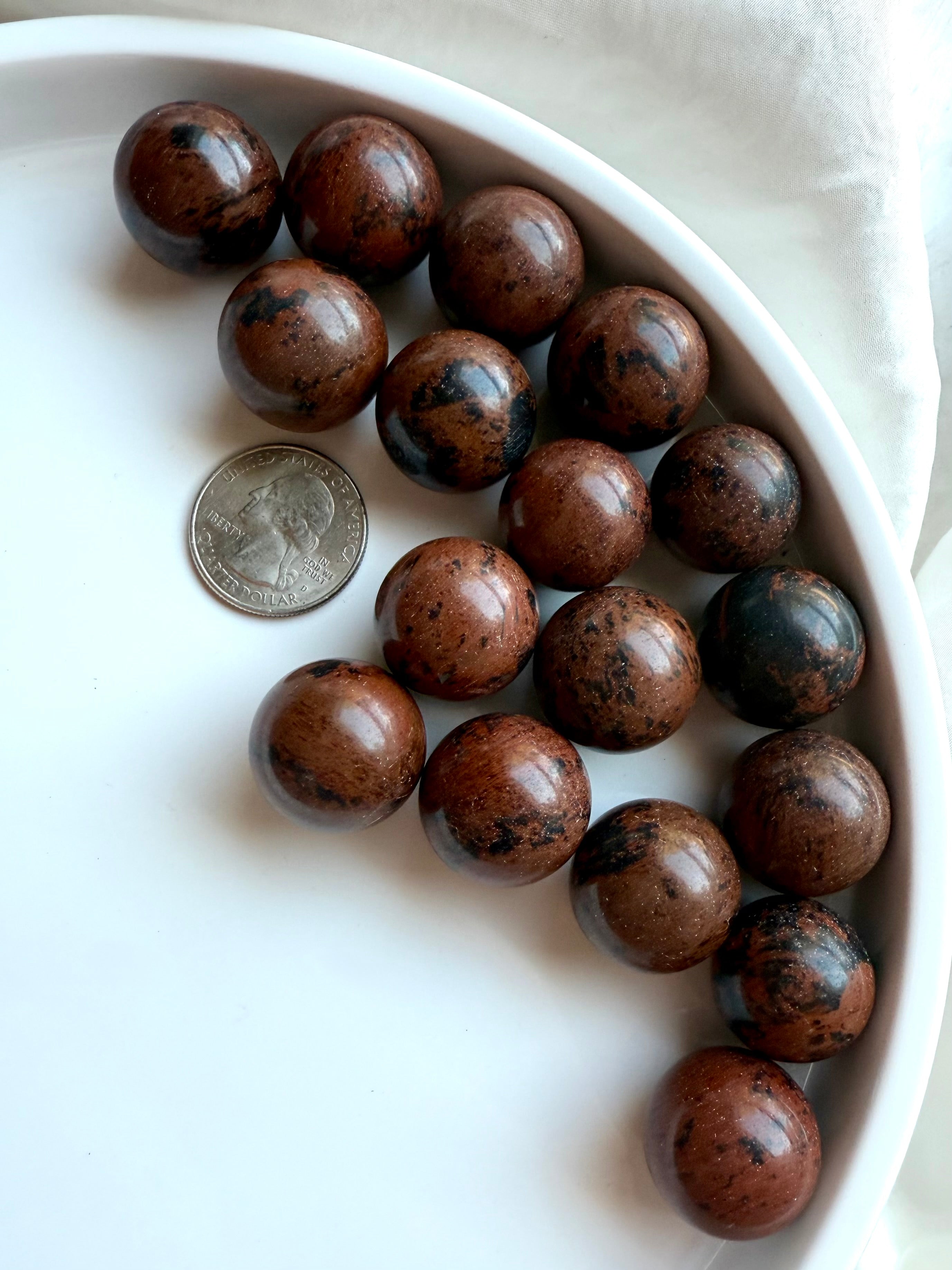 Multiple Mahogany Obsidian mini crystal spheres with quarter for scale – grounding and protective stones
