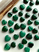 Mini Malachite crystal hearts arranged on a white plate with palo santo and selenite for sacred altar styling