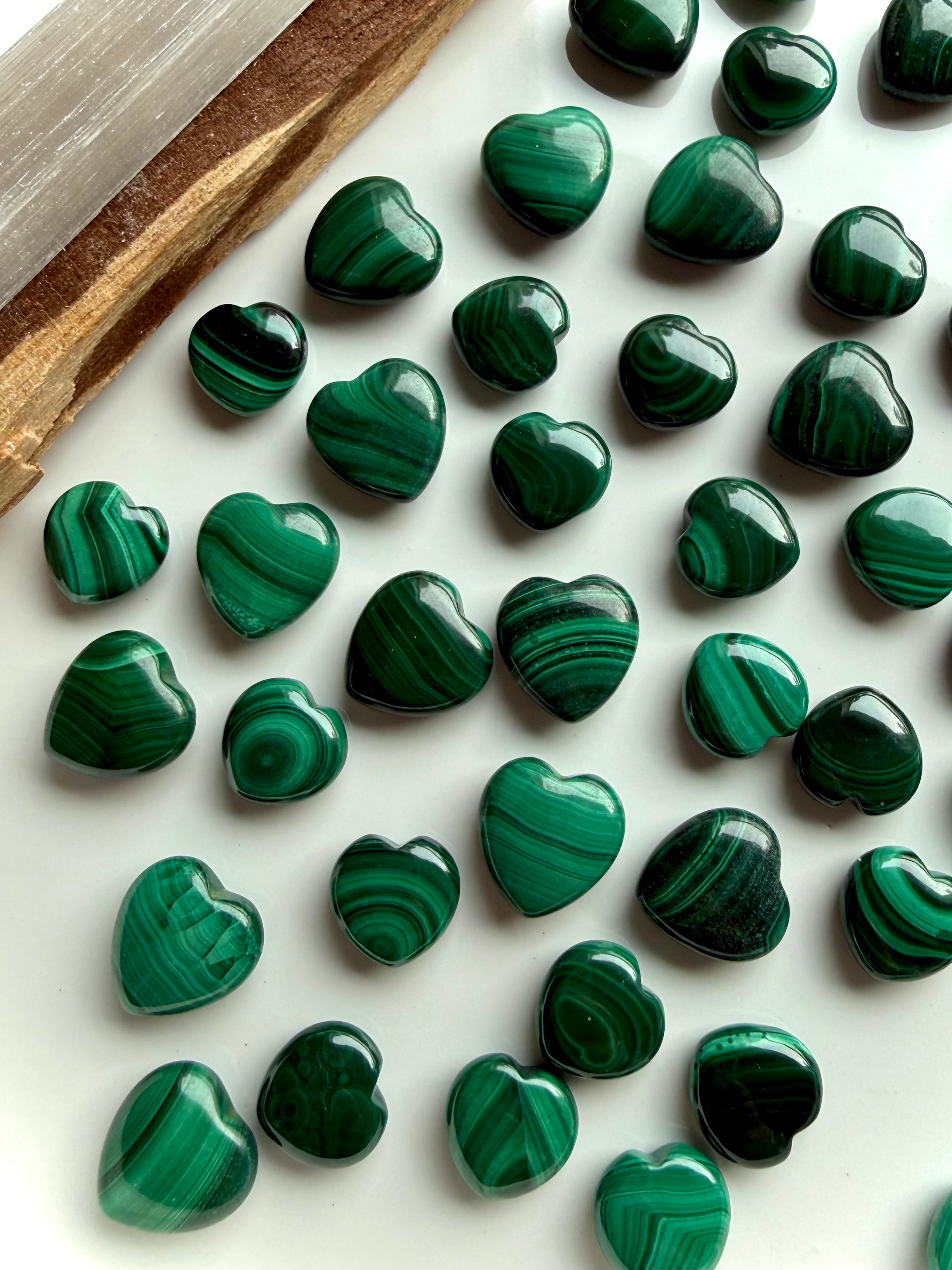 Mini Malachite crystal hearts arranged on a white plate with palo santo and selenite for sacred altar styling
