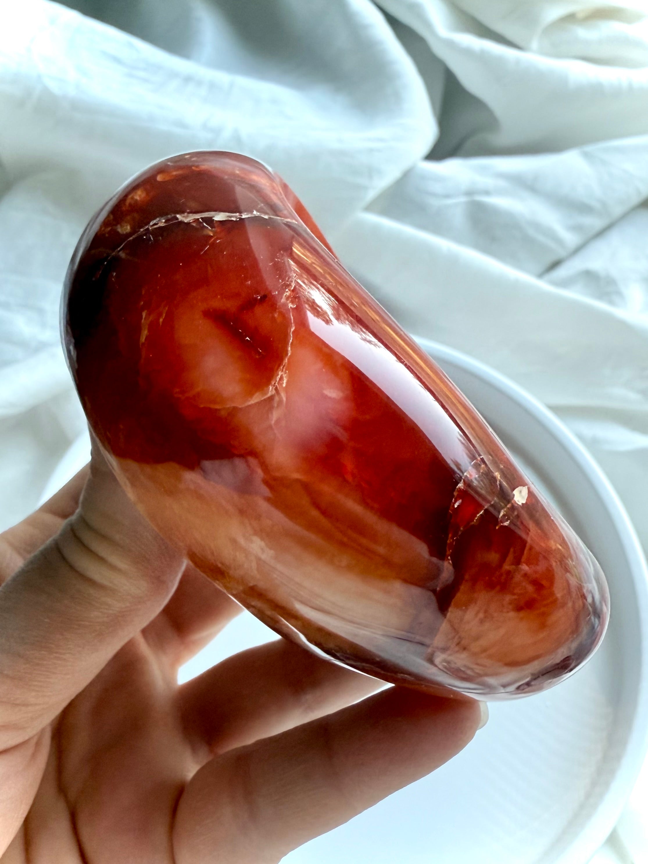 Side view of Carnelian gemstone bowl showing natural banding and curved shape, hand-carved crystal offering dish