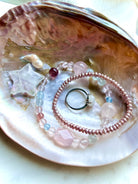 pink freshwater pearl bracelet styled in shell dish with mixed gemstone bracelet and moonstone ring, crystal star accent, heart chakra jewelry styling