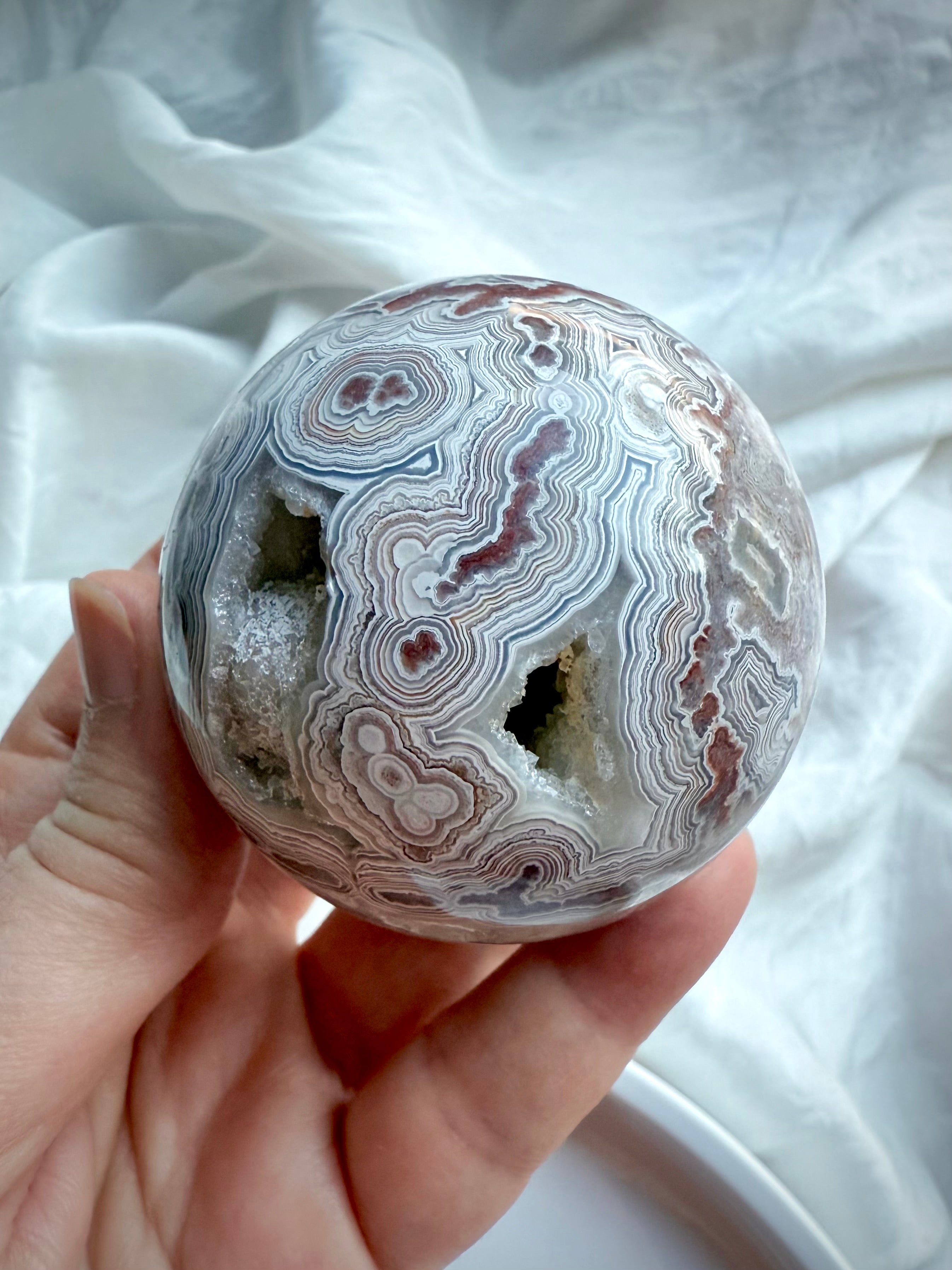 Root Chakra Crazy Lace Agate sphere with multiple geode windows, radiant pink quartz sparkle, and vibrant earth-tone patterning