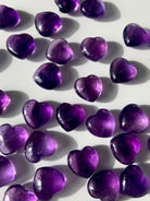 Array of gemmy purple Amethyst hearts on a white background — mini crystals for crown chakra healing
