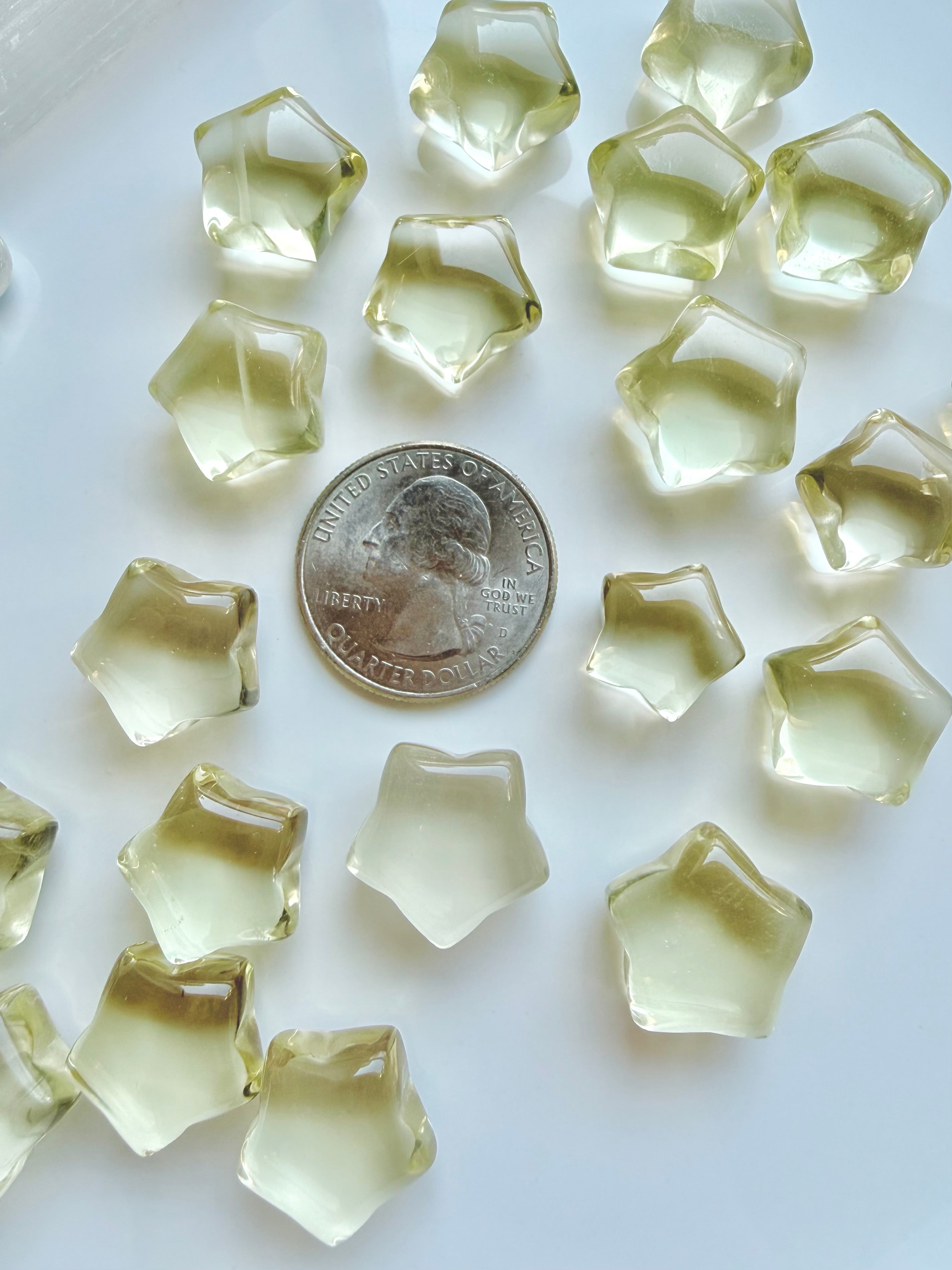 Mini Lemon Citrine stars shown with a US quarter to show their petite scale and golden-yellow color