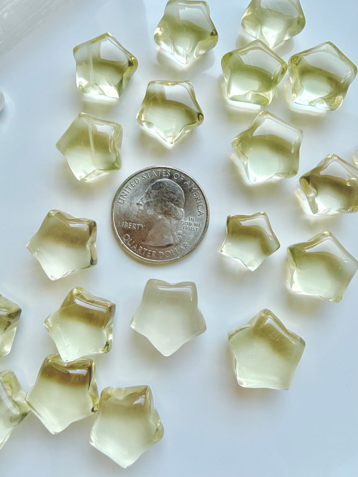 Mini Lemon Citrine stars shown with a US quarter to show their petite scale and golden-yellow color
