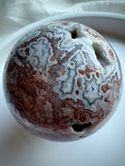 Crazy Lace Agate sphere showing vivid red and cream swirls with grounding crystal energy