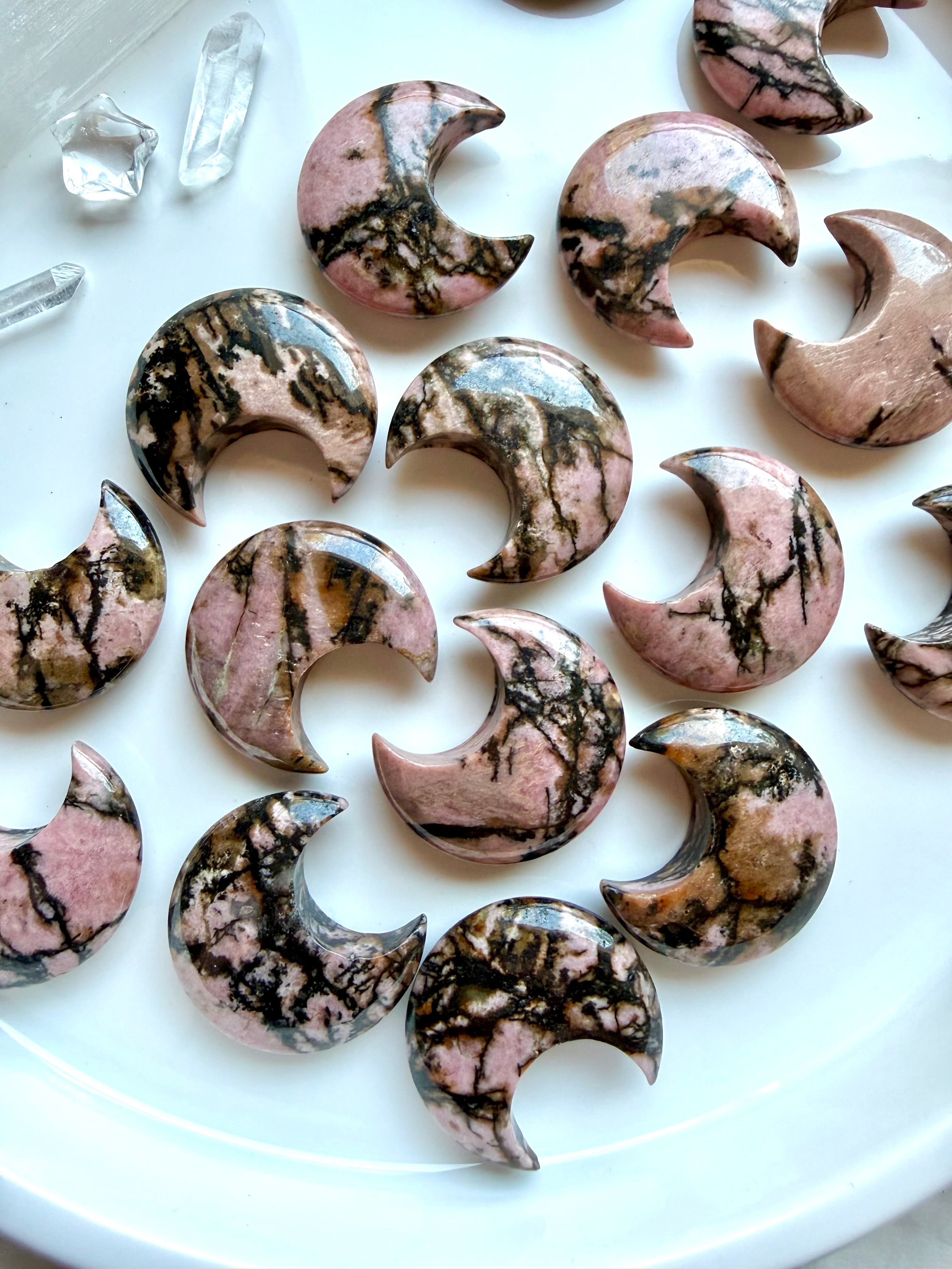 Collection of Rhodonite crescent moon crystals with unique natural patterns for emotional healing and self-love