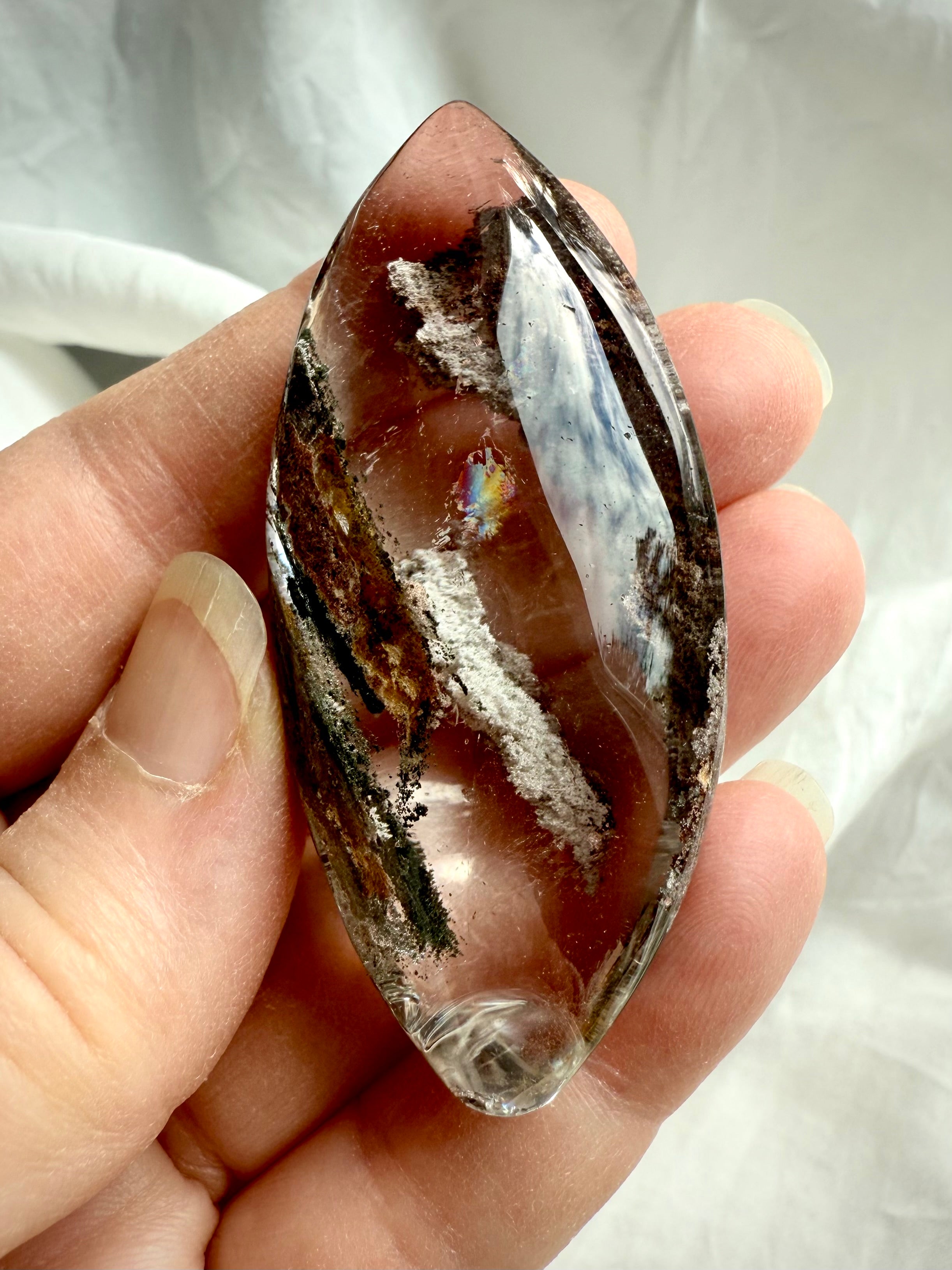 Garden Quartz marquise lens held in hand, showing scale, rainbows, and detailed phantom inclusions