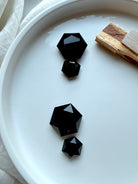 Black Obsidian faceted hexagon set showing size variations beside Palo Santo and Selenite — grounding protection stones for root chakra balance and clearing negativity.