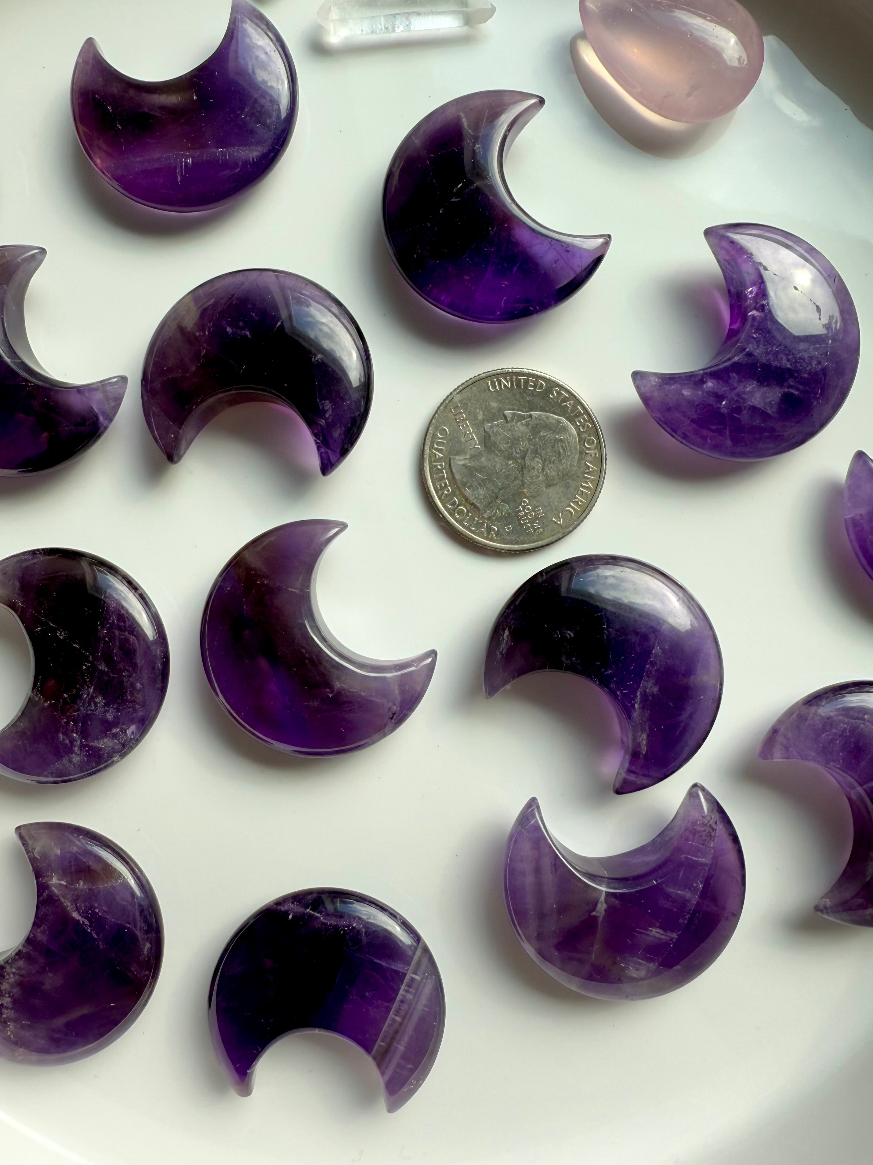 High quality deep purple Dream Amethyst Moons shown on a white plate with a quarter for scale